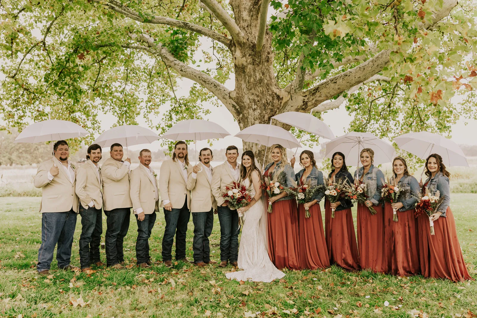 Bride and groom smiling with their wedding party outside.