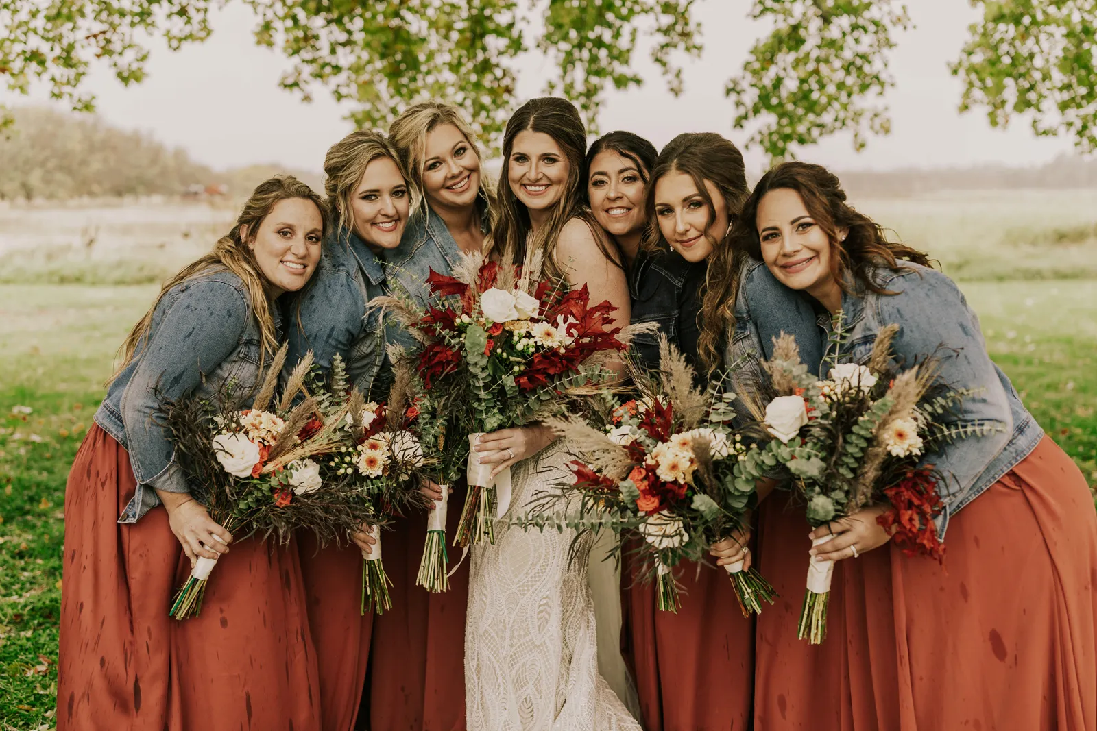 Bride surrounded by bridesmaids and smiling at the camera.