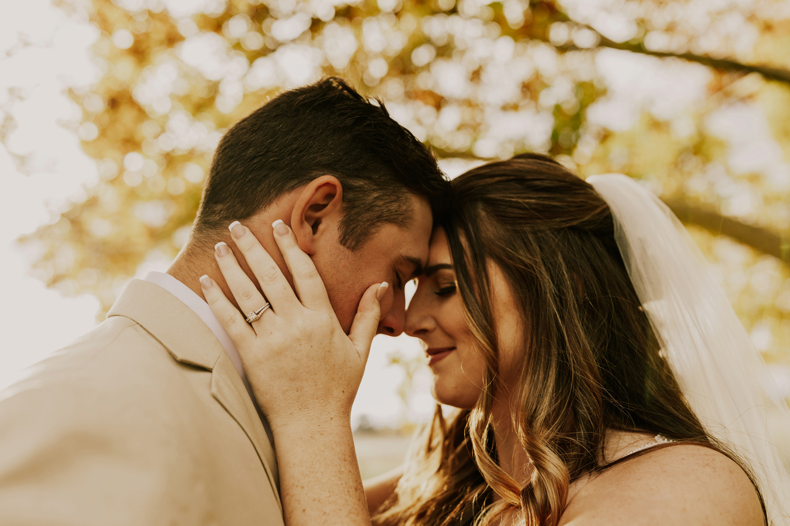 Bride holding her husbands face and smiling.