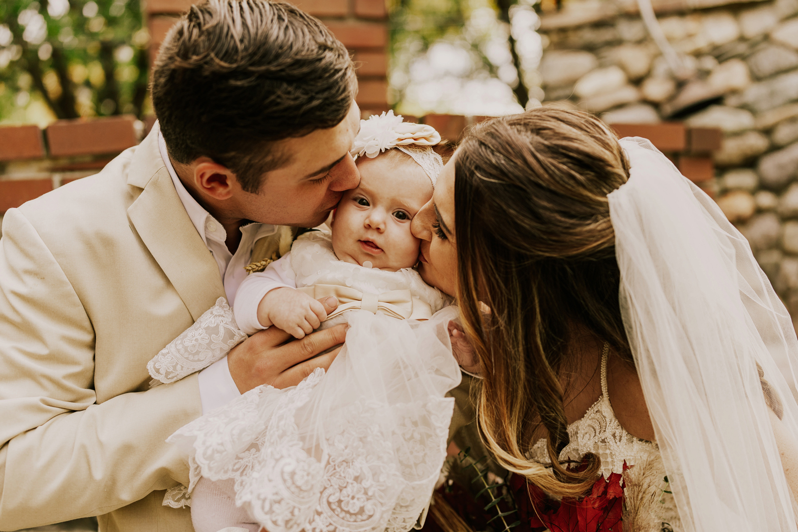 Bride and groom kissing the cheeks of a baby.