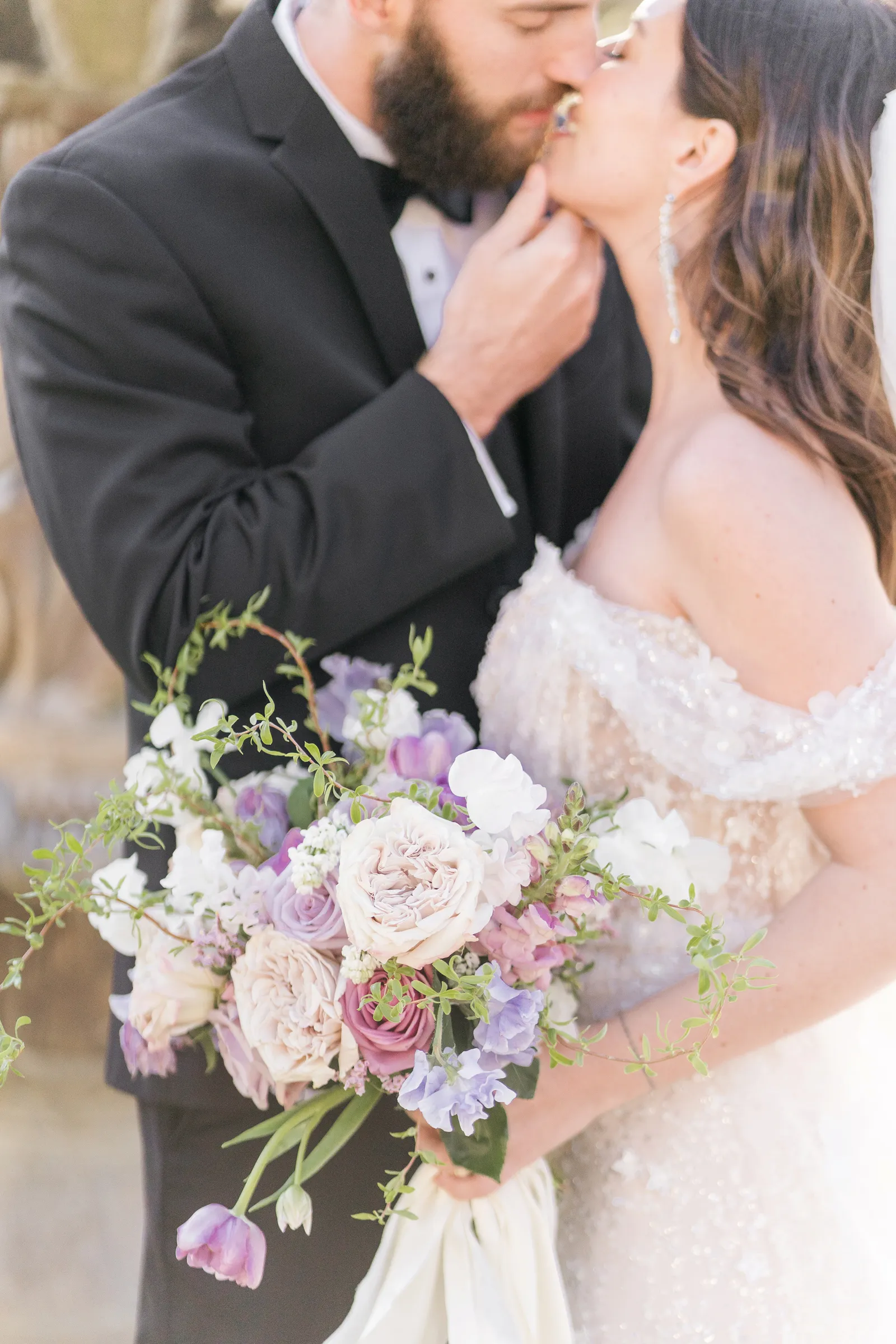 Close up photo of a groom's hand grabbing his wife's chin.