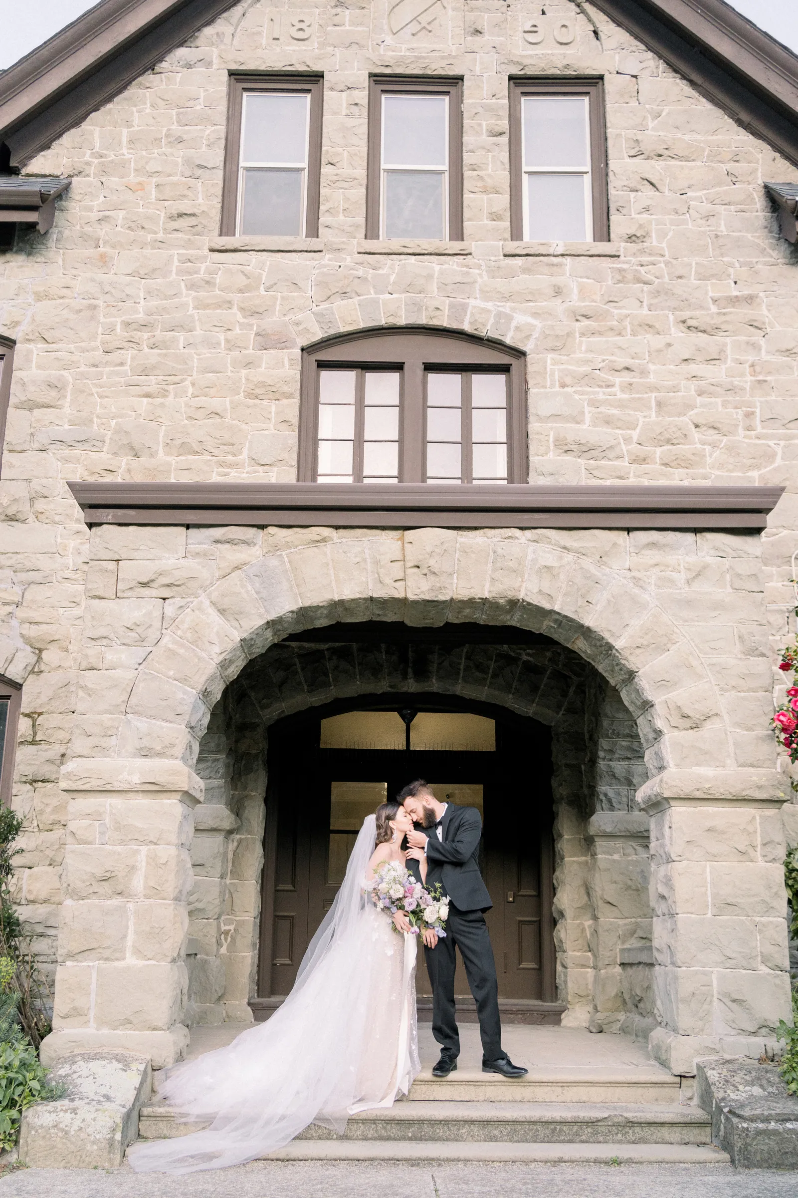 Bride and groom kissing in front of a house.