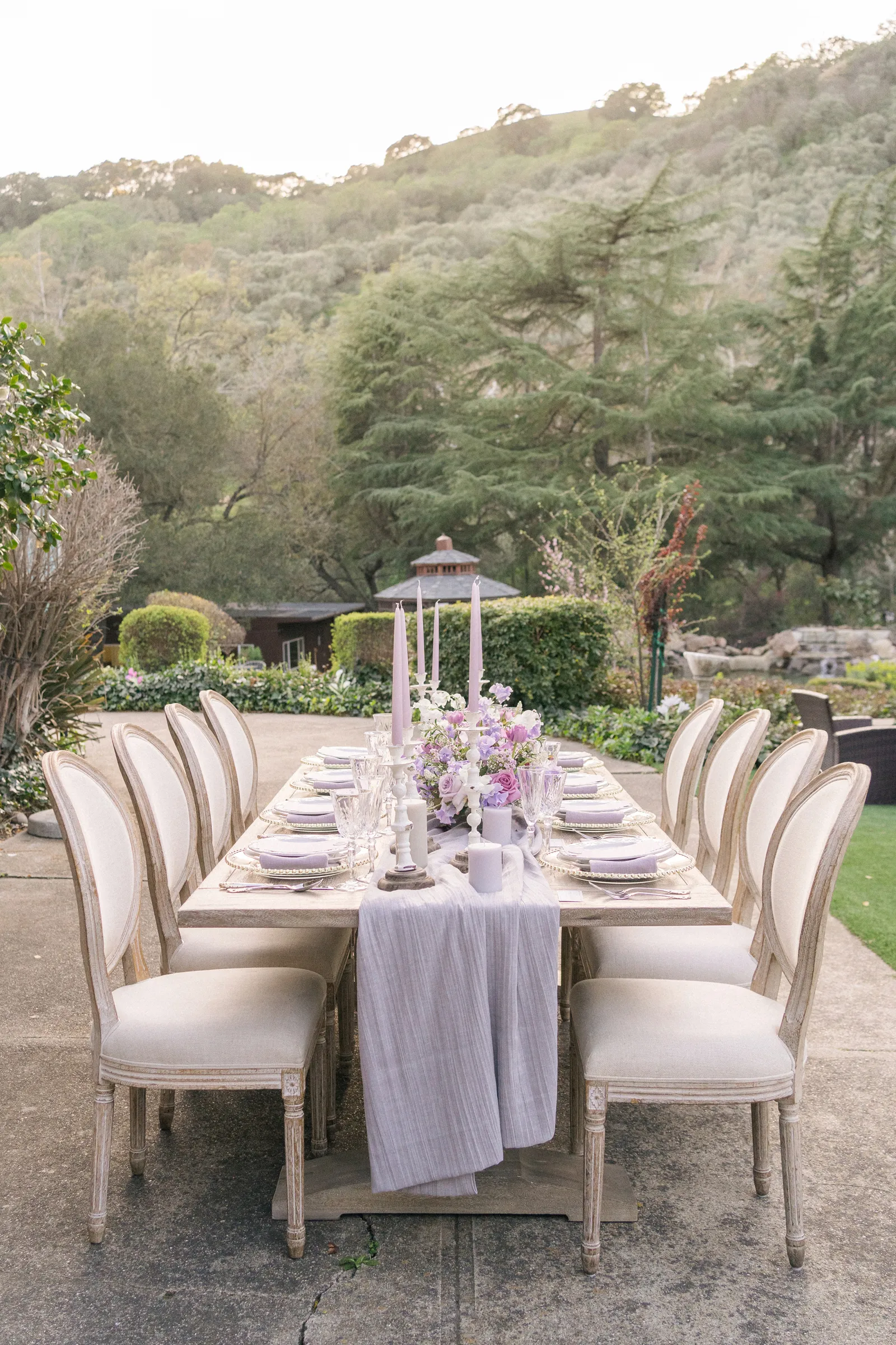 Outside dining table with chairs, candles, and plates.