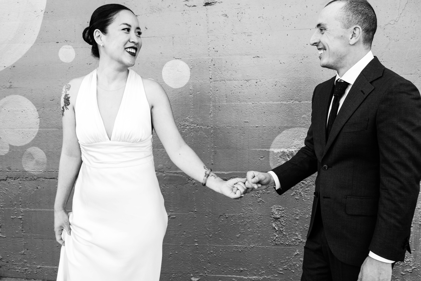 Black and white photo of the bride and groom holding hands and laughing.