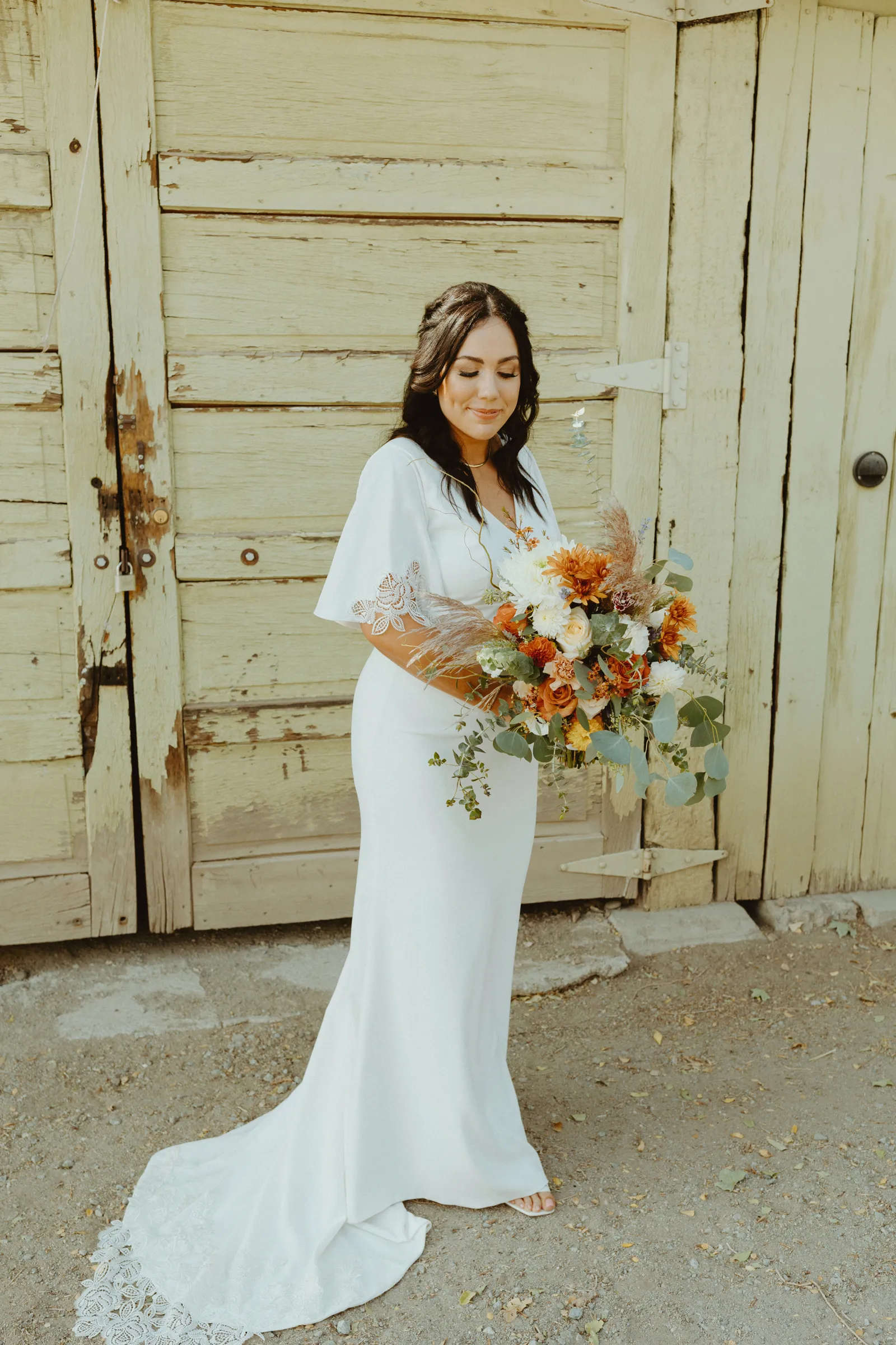 Bride posing with her bouquet and looking down.