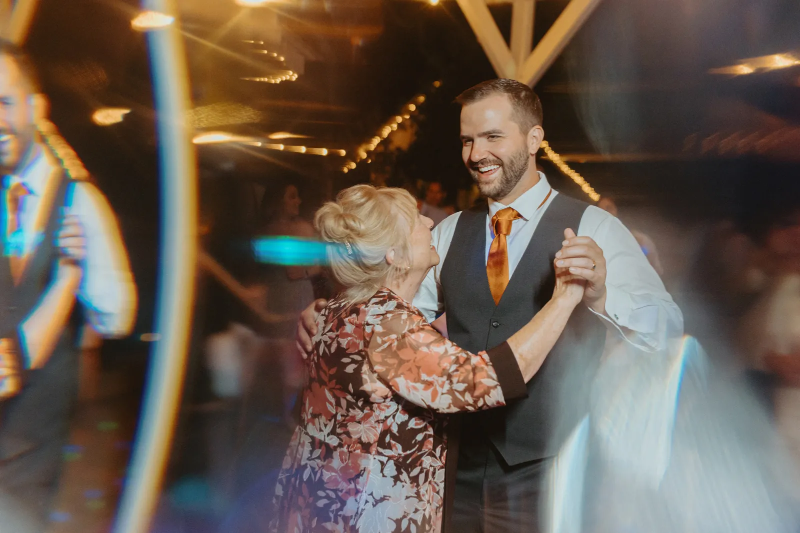 Groom and his mother dancing together and laughing.