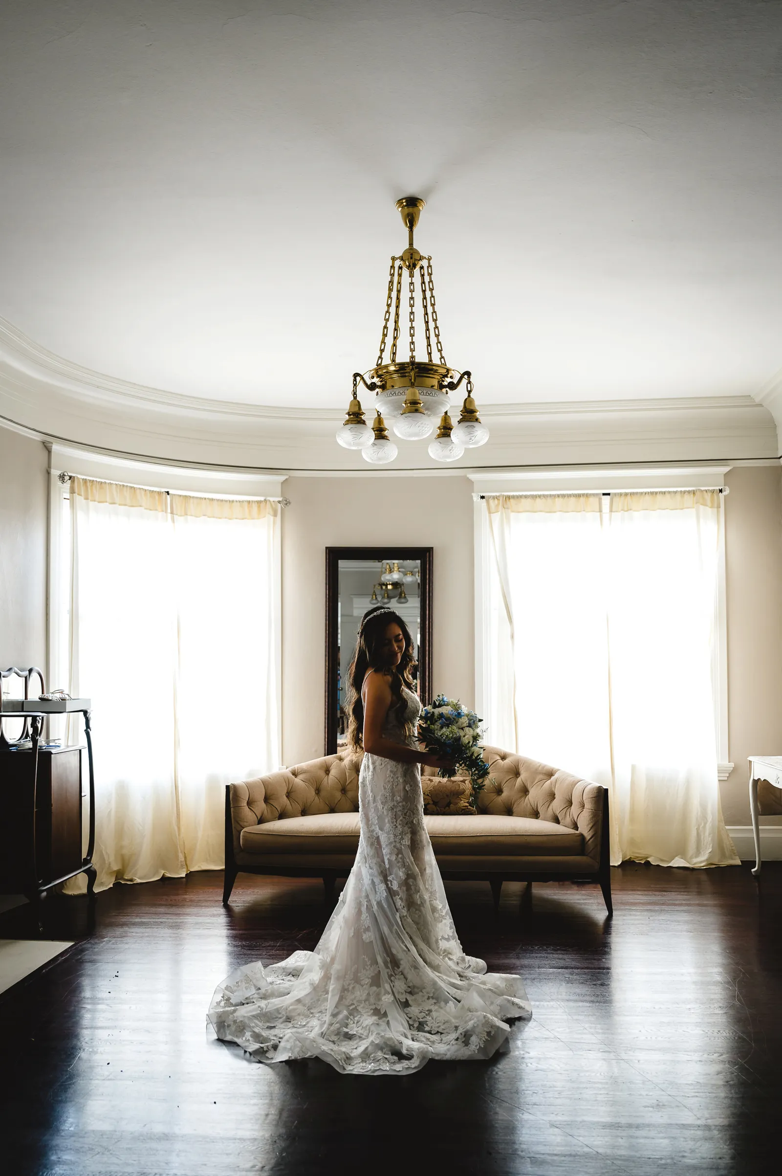 Far away photo of a bride inside a mansion holding her flowers.