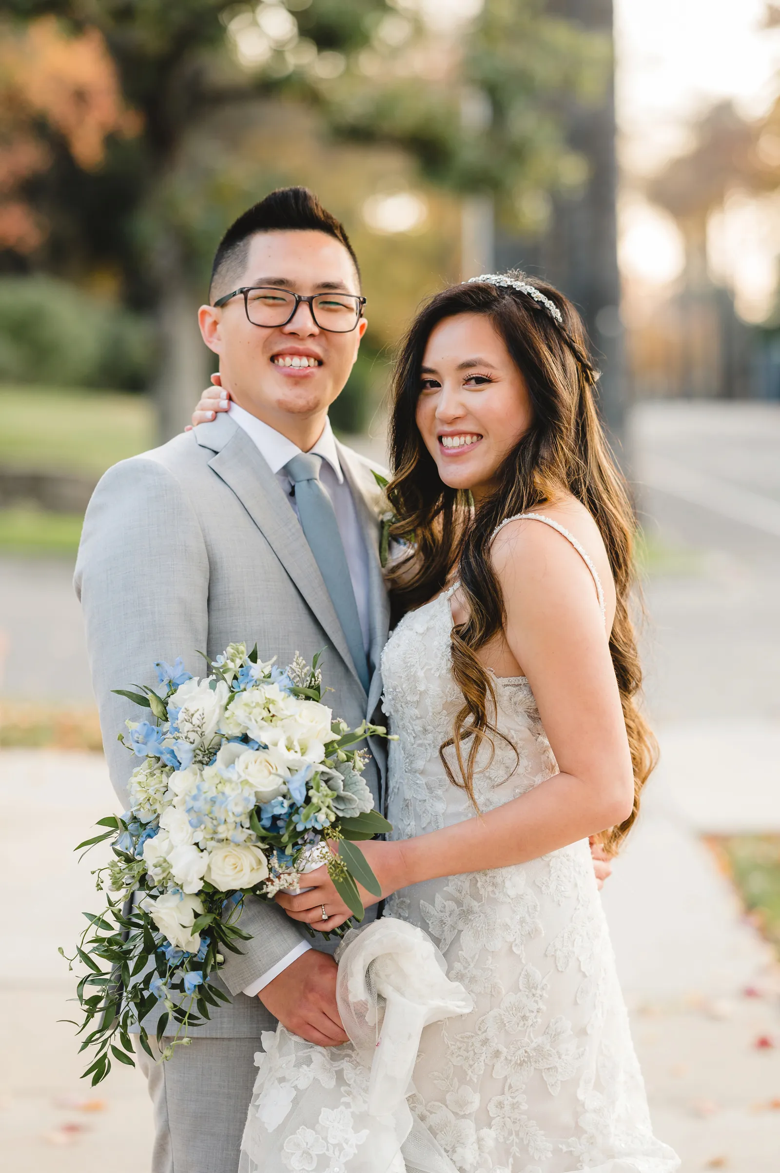 Bride and groom holding hands and smiling at the camera.