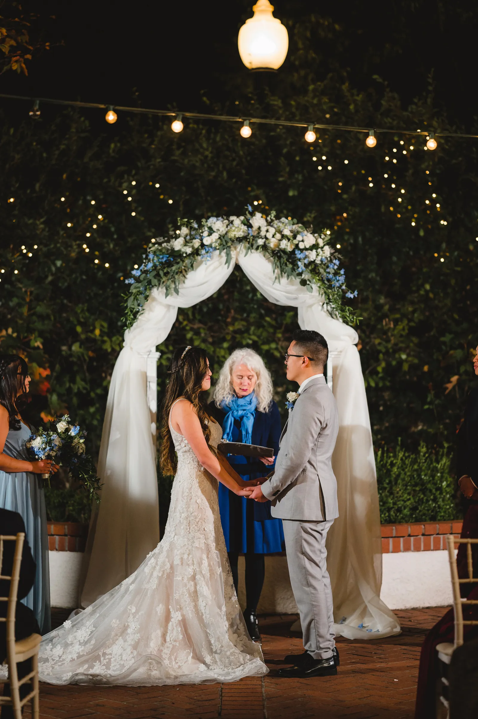 Bride and groom holding hands at the altar at night.