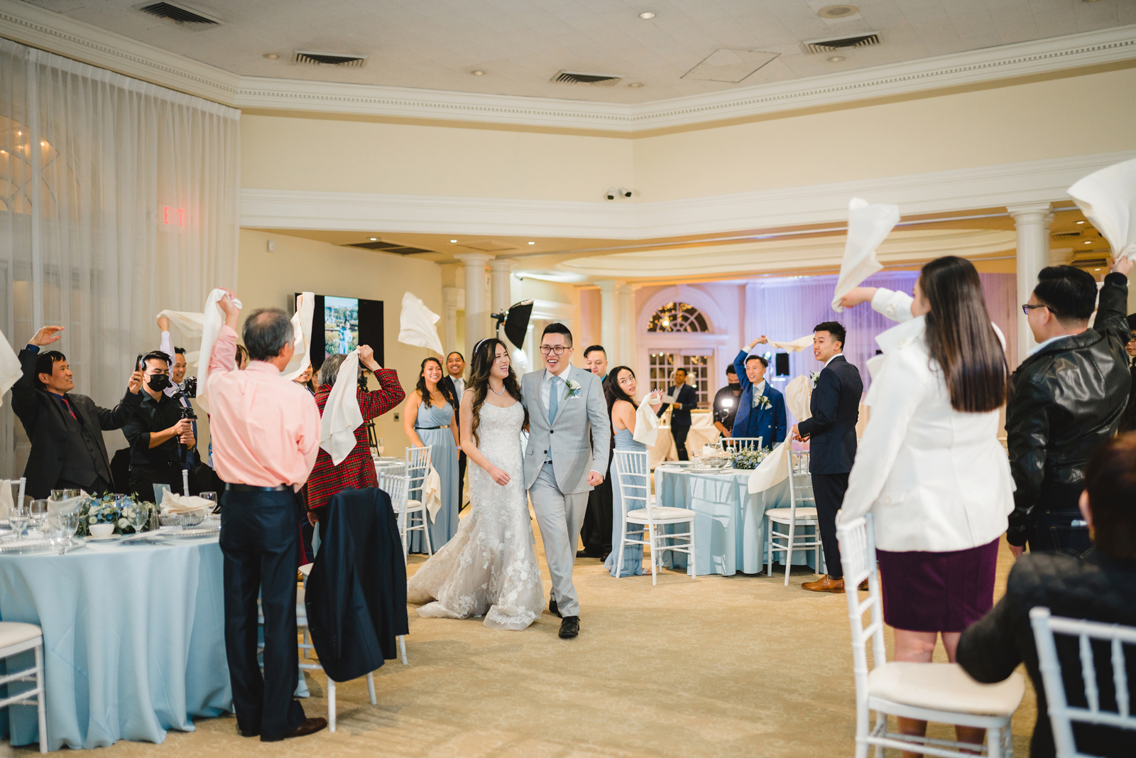 Newlyweds walking into their reception with all their friends and family celebrating.