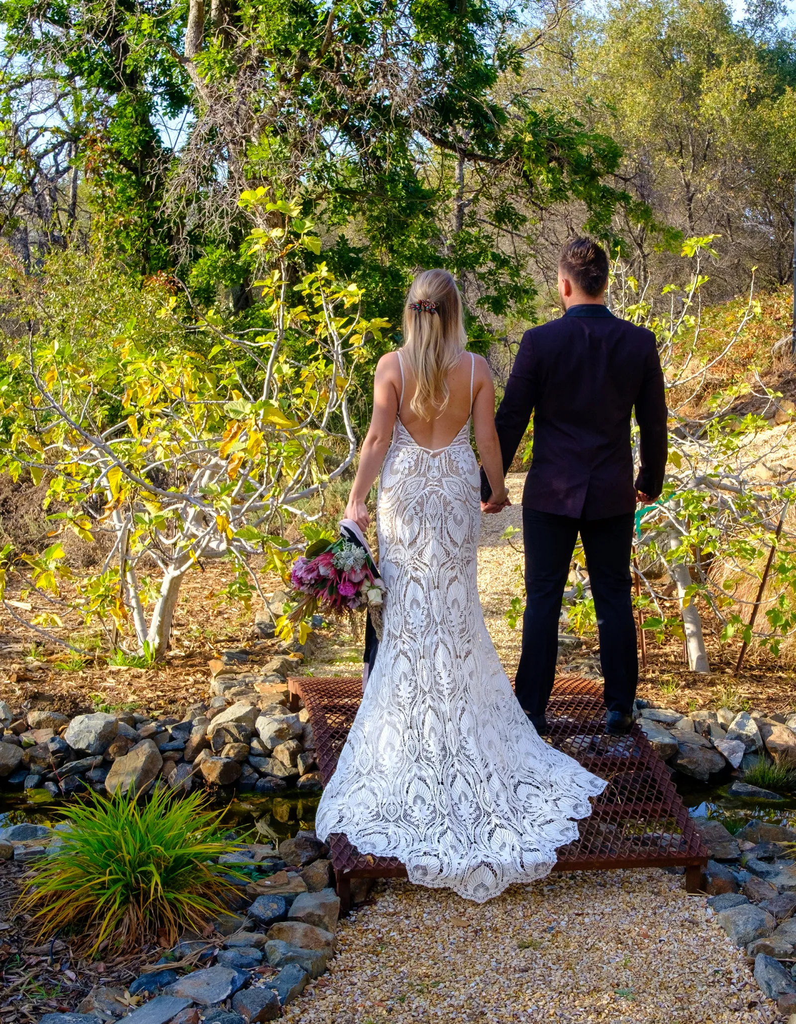 Photo of a groom and bride walking outside from the back.