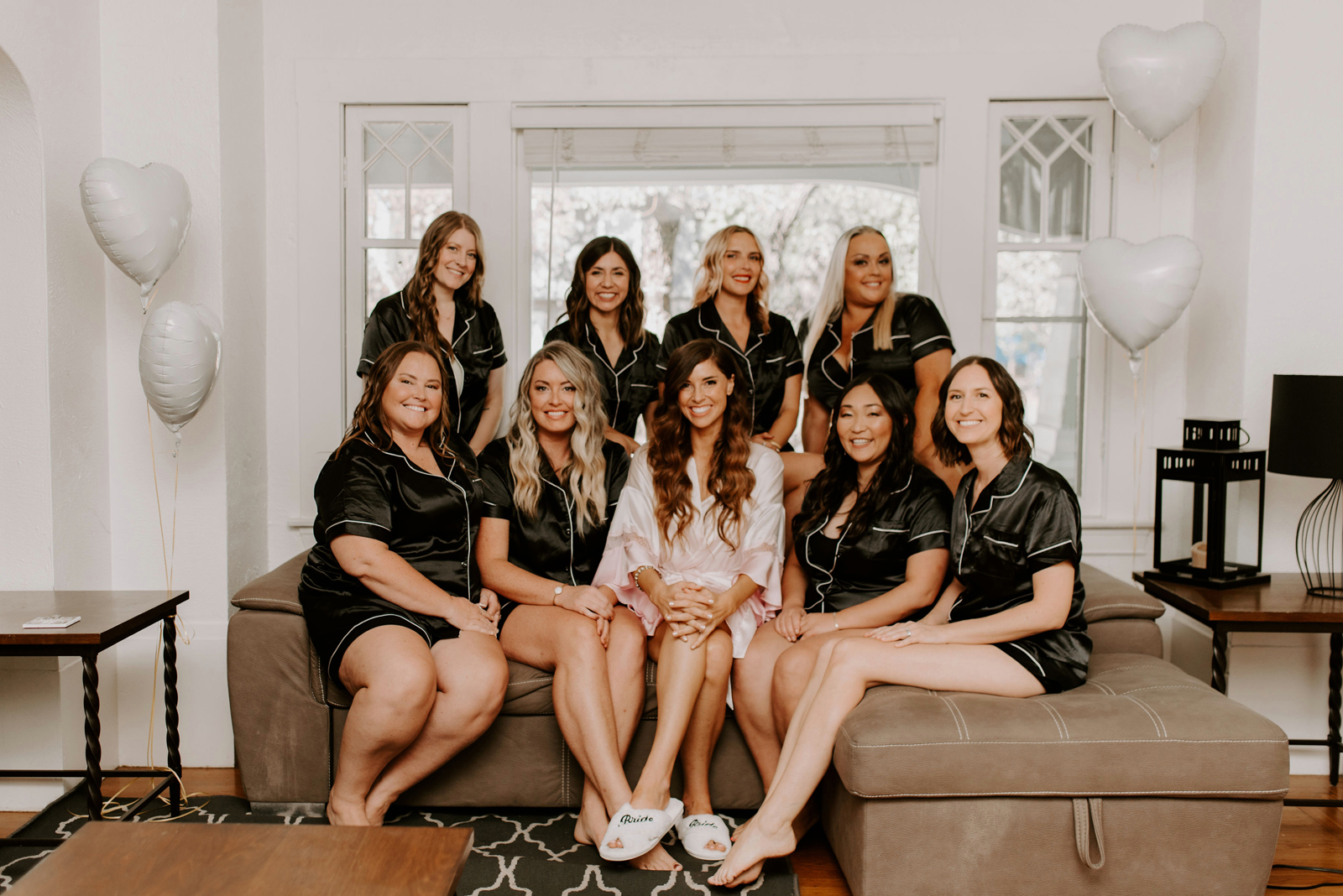 Bride and her bridal party smiling together in their robes on a couch.