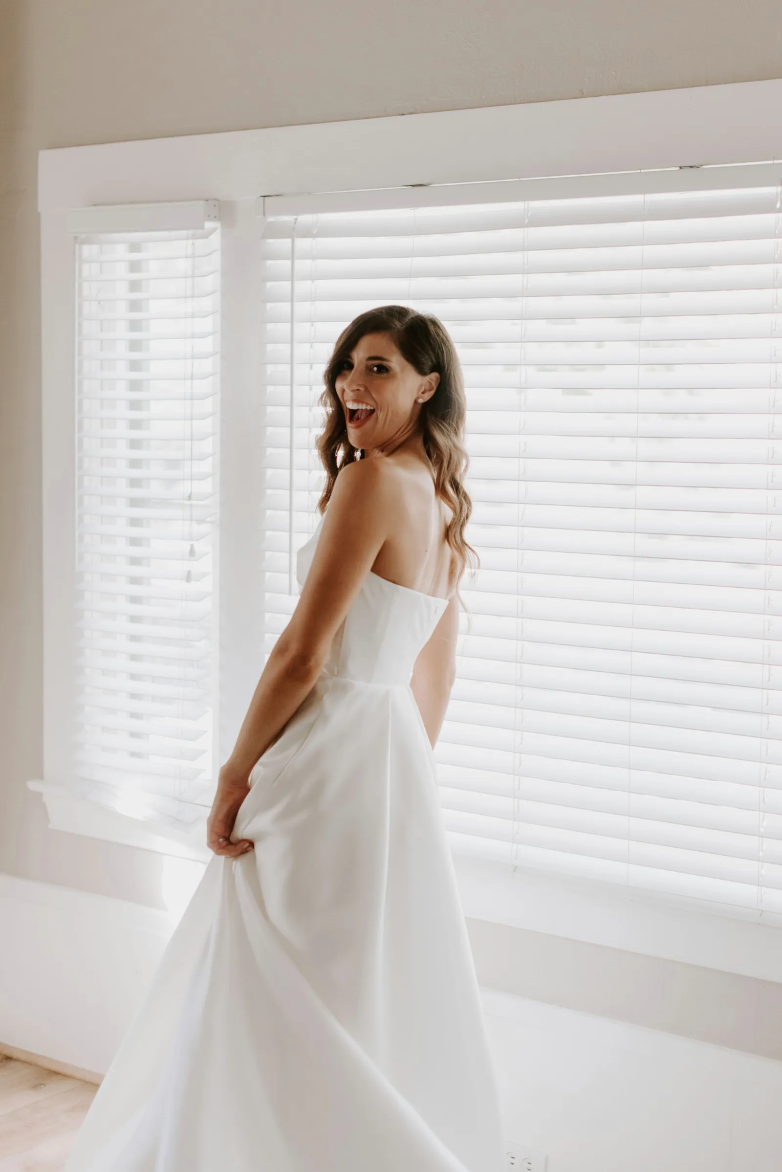 Bride holding her dress, twirling and smiling at the camera.