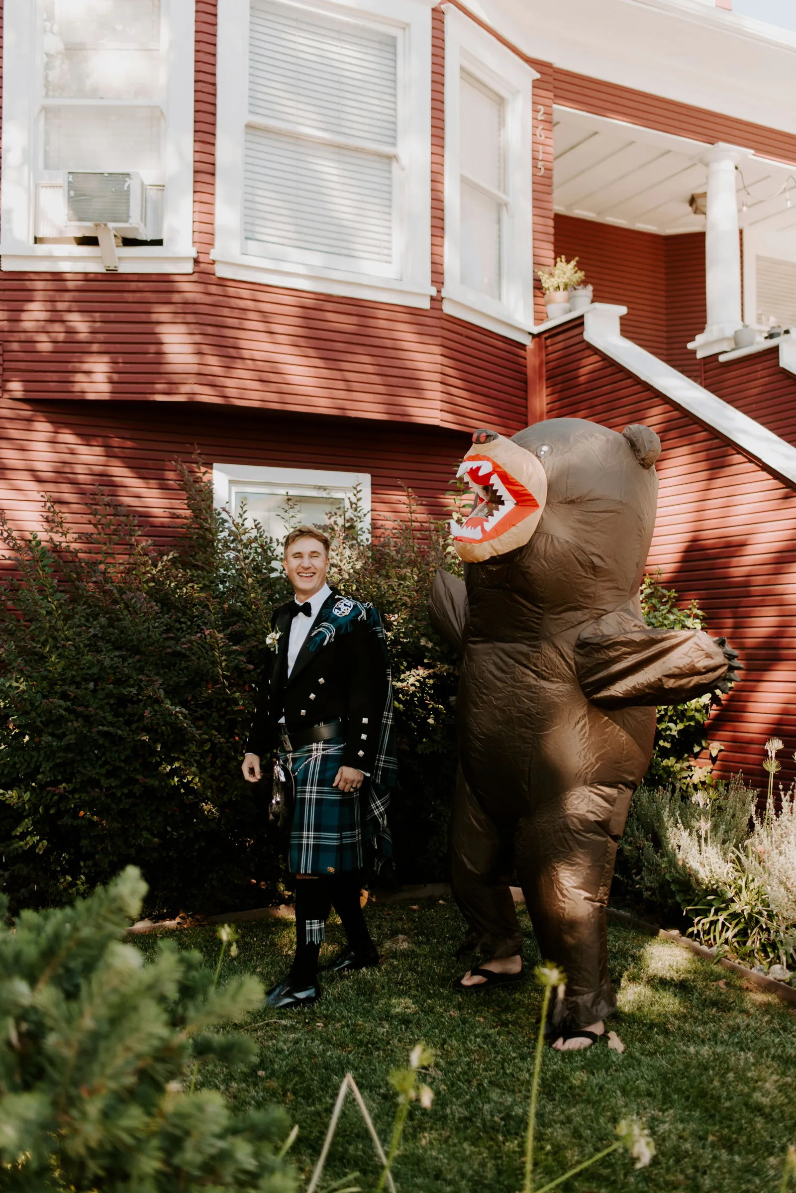 Groom laughing as he is pranked during his first look by a friend in a bear suit.