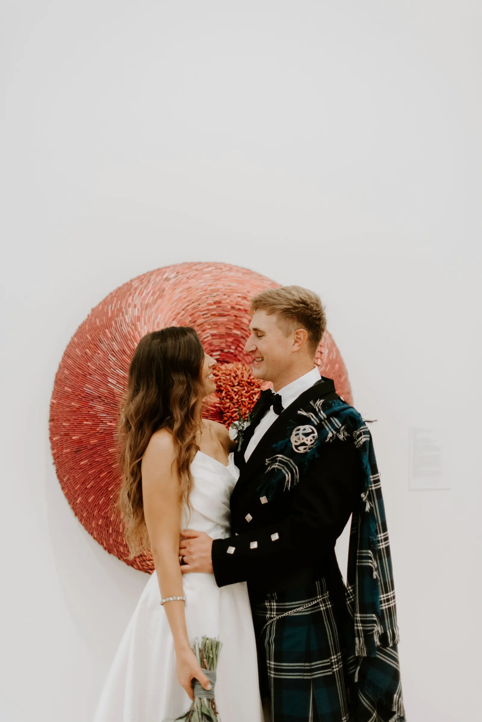 Bride and groom smiling at each other in the Crocker Art Museum.