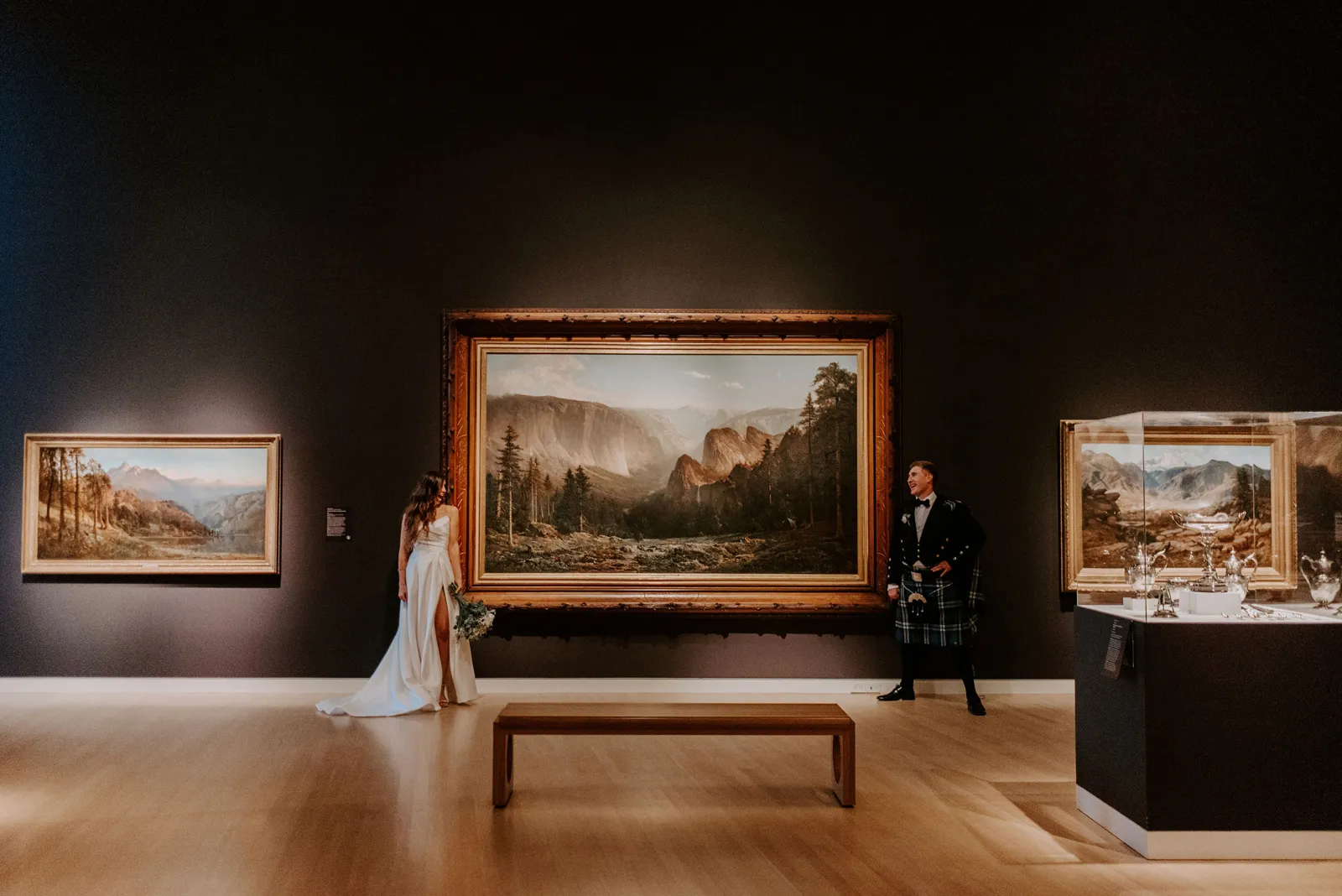 Bride and groom standing alongside a large painting.