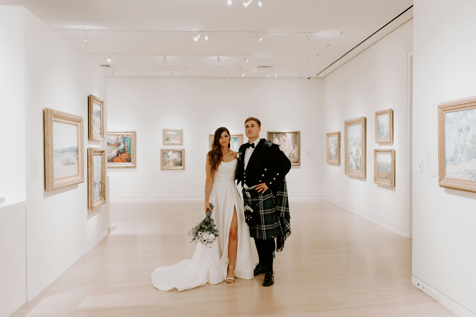 Bride and groom smiling in a room full of art and paintings.