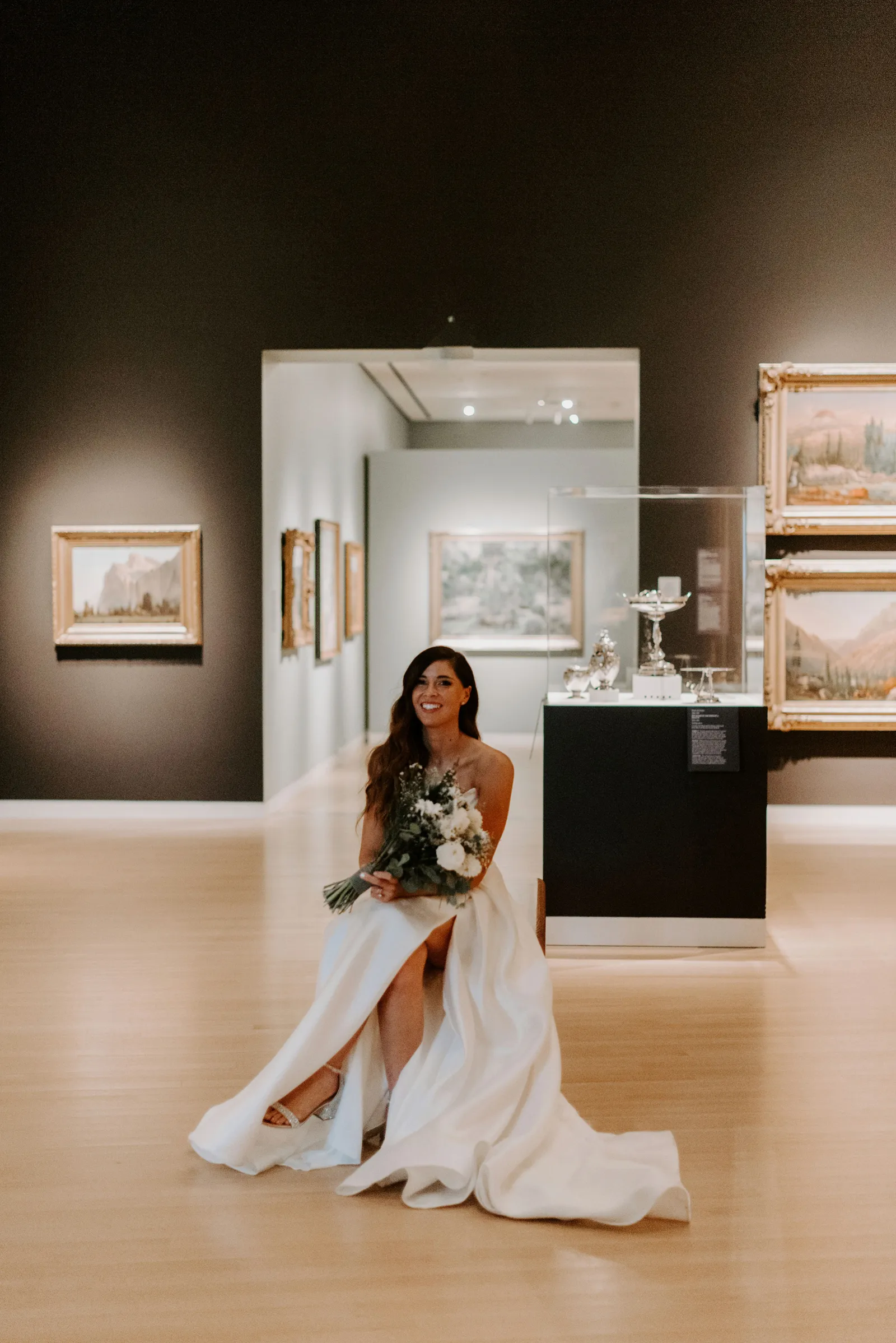 Bride sitting and smiling in a room full of art and paintings.