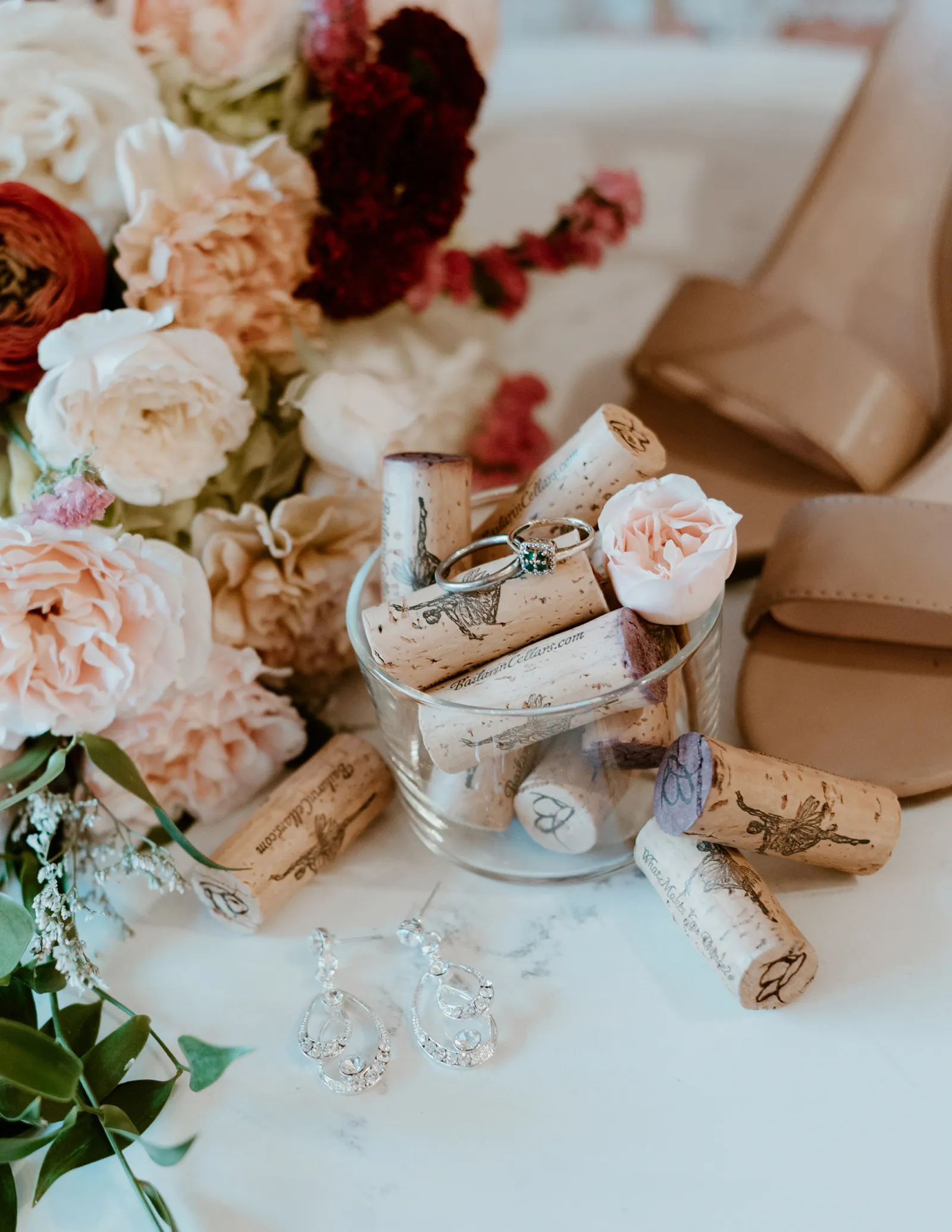 Close up photo of engagement rings sitting in a glass container full of wine corks.