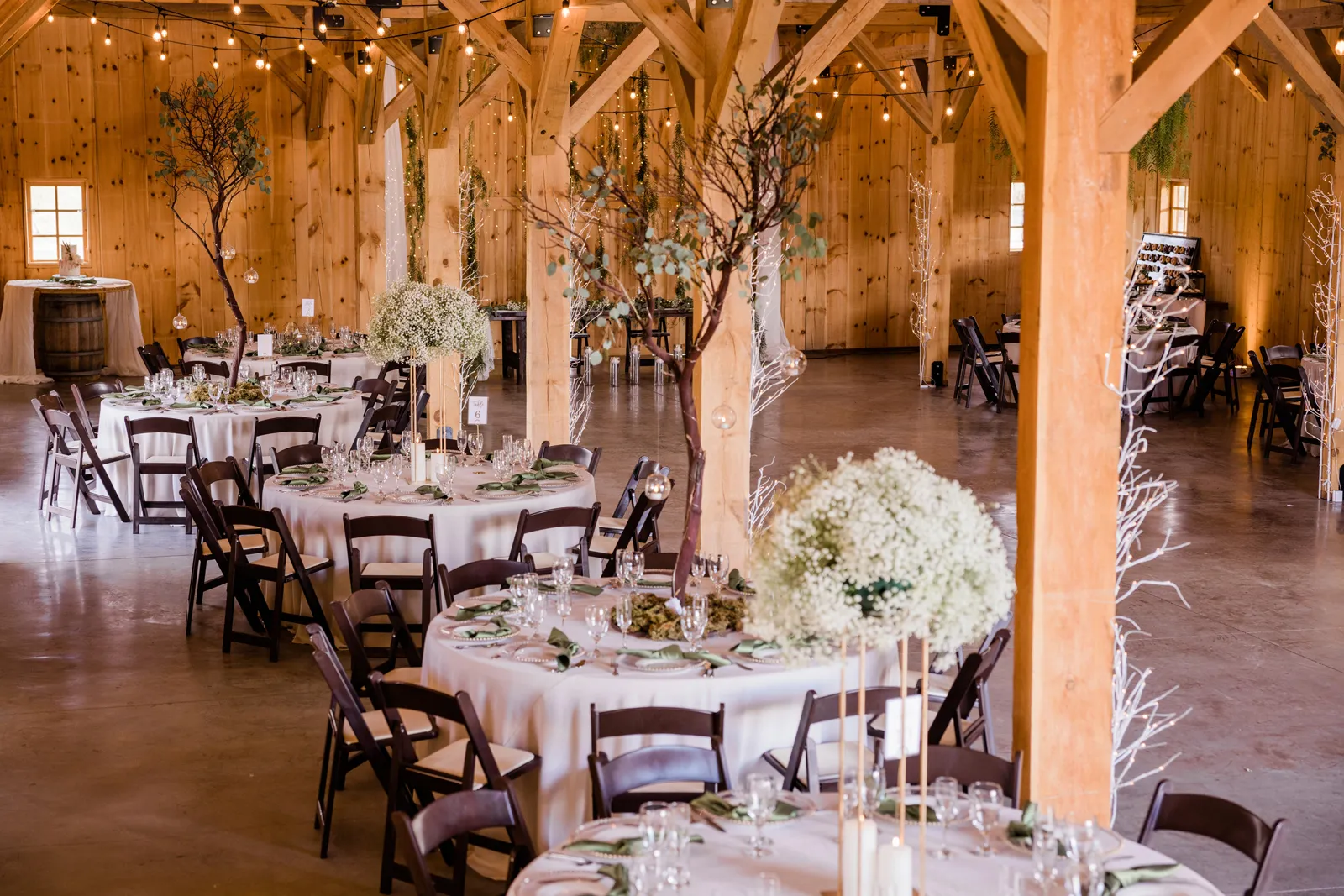 Photo of the reception venue with circular tables inside a barn.