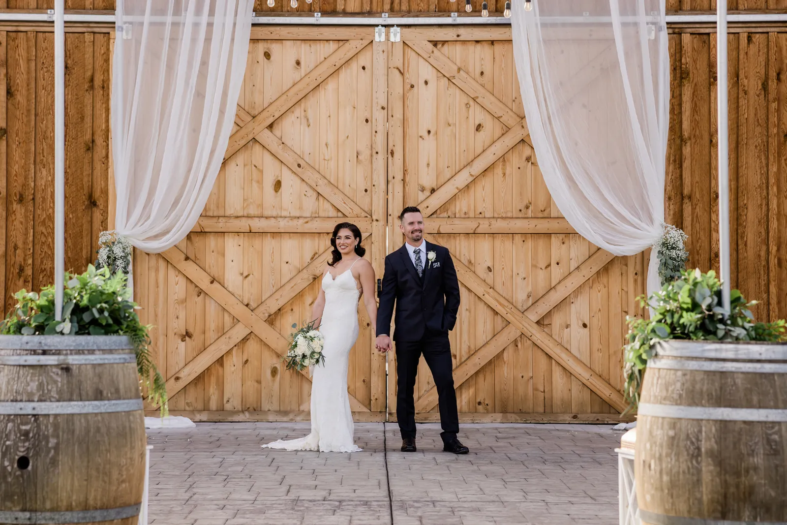 Bride and groom posing in front of the large barn.