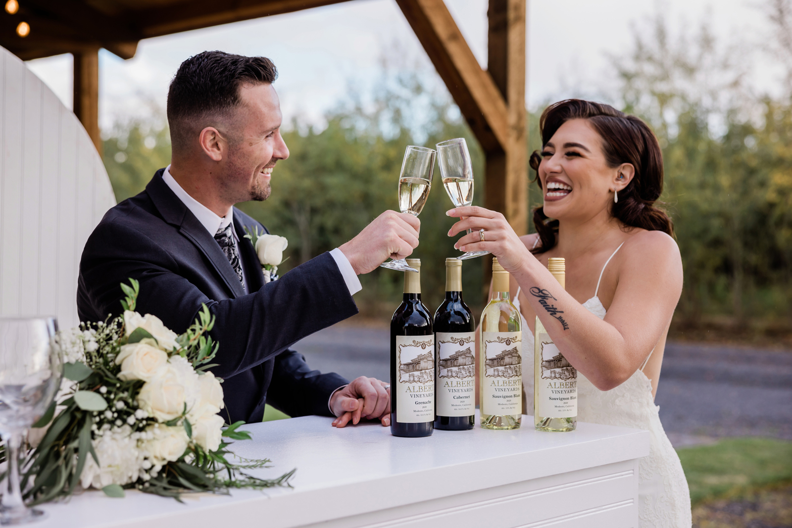 Bride and groom laughing as they cheers with their wine glasses.