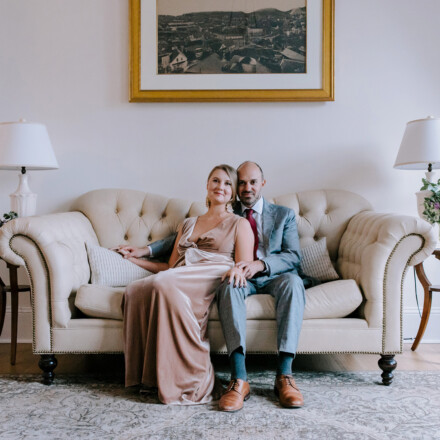 Bride and groom posing together on a white couch before their wedding.