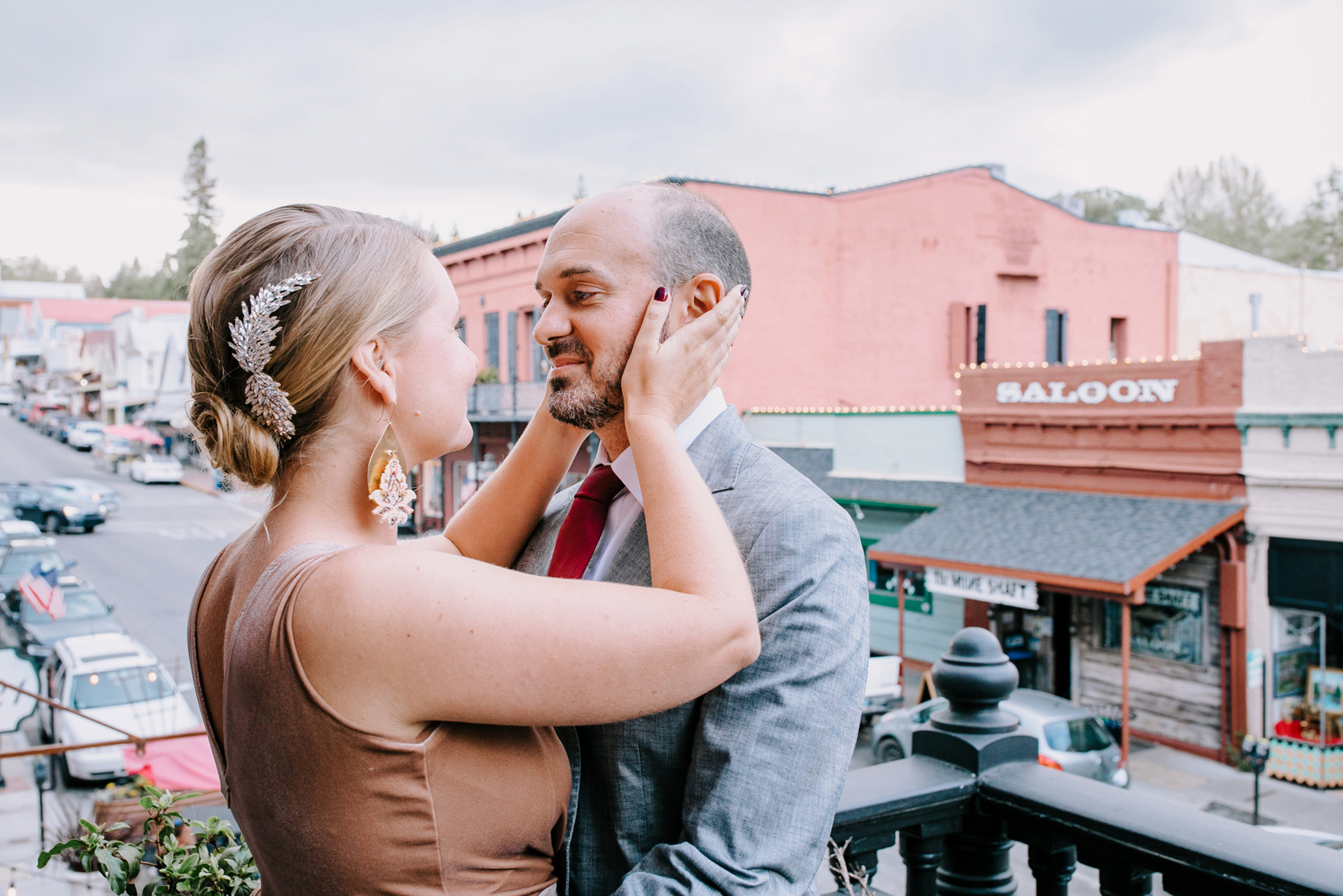 Bride-to-be holding her groom's face on a balcony.