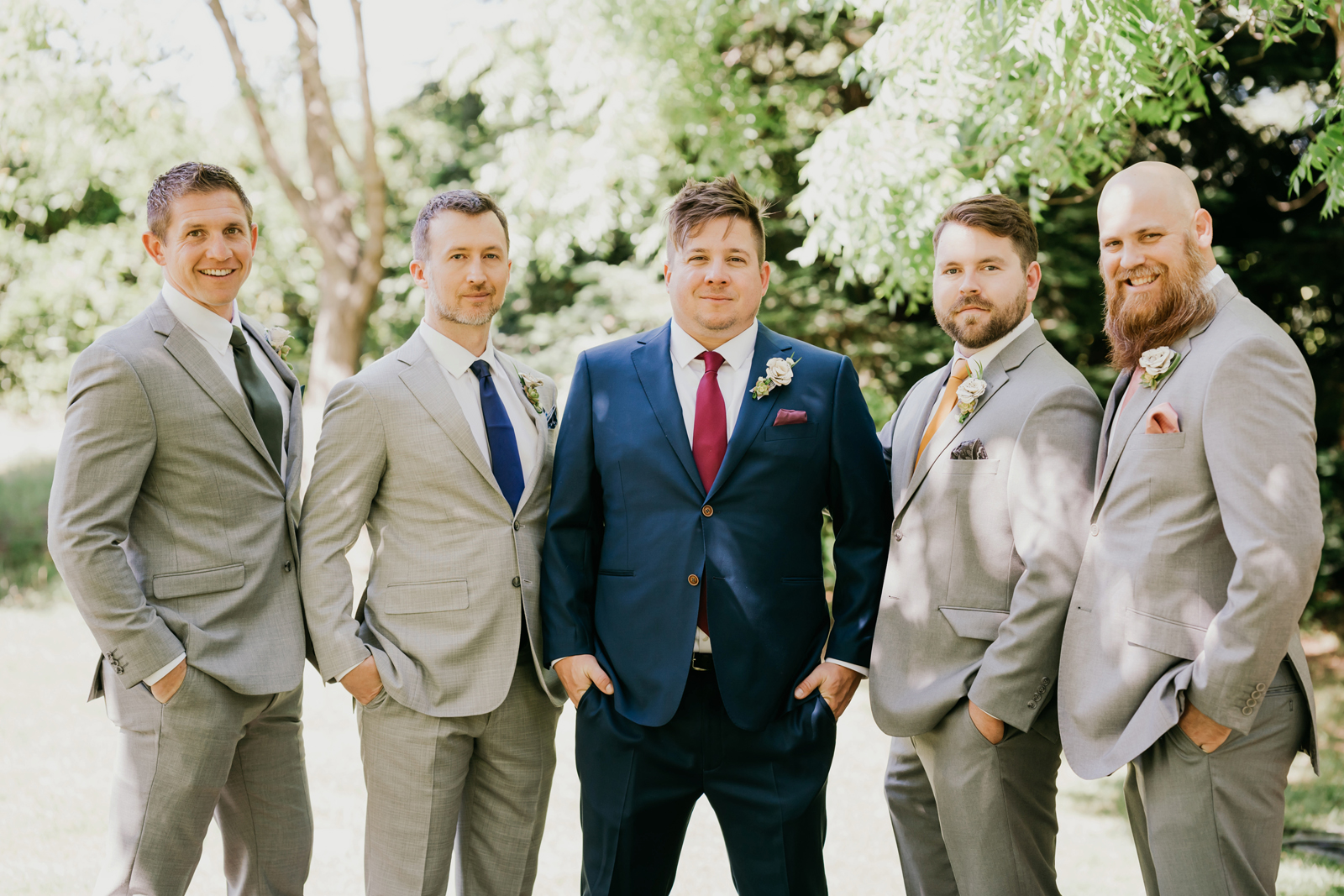 Groom and his groomsmen posing with their hands in their pockets.