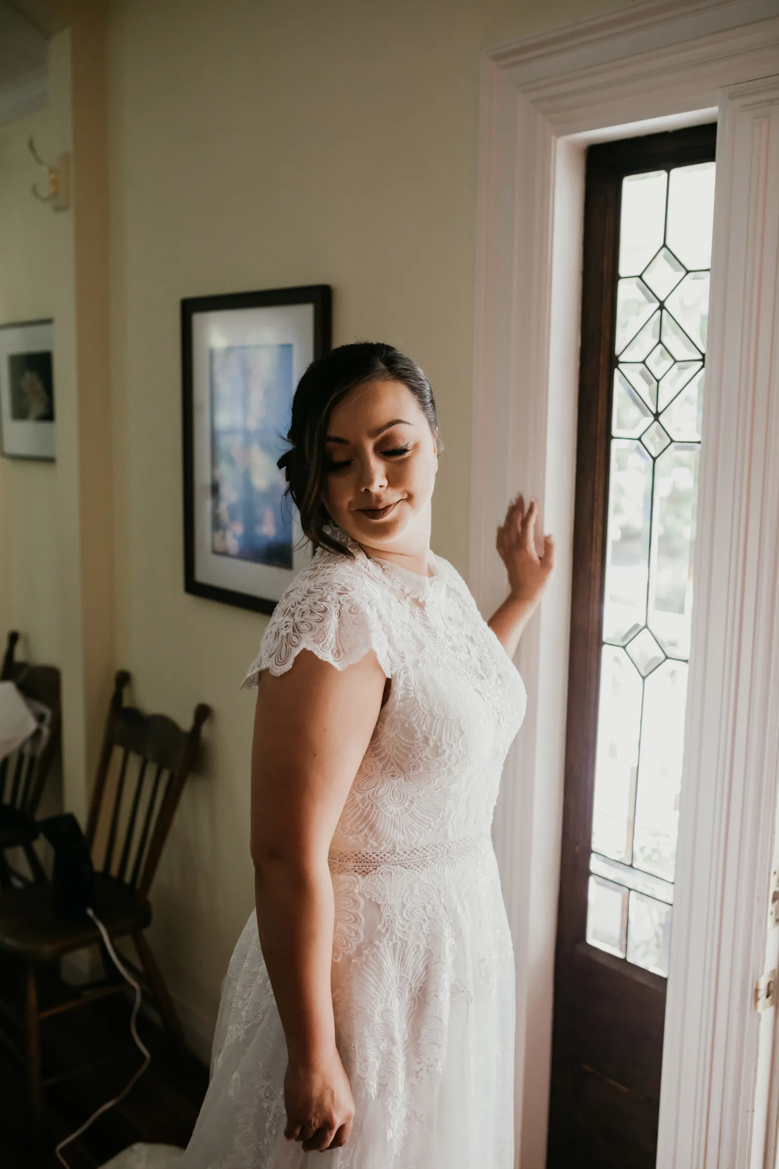 Bride posing with her hand on the doorframe, looking down.