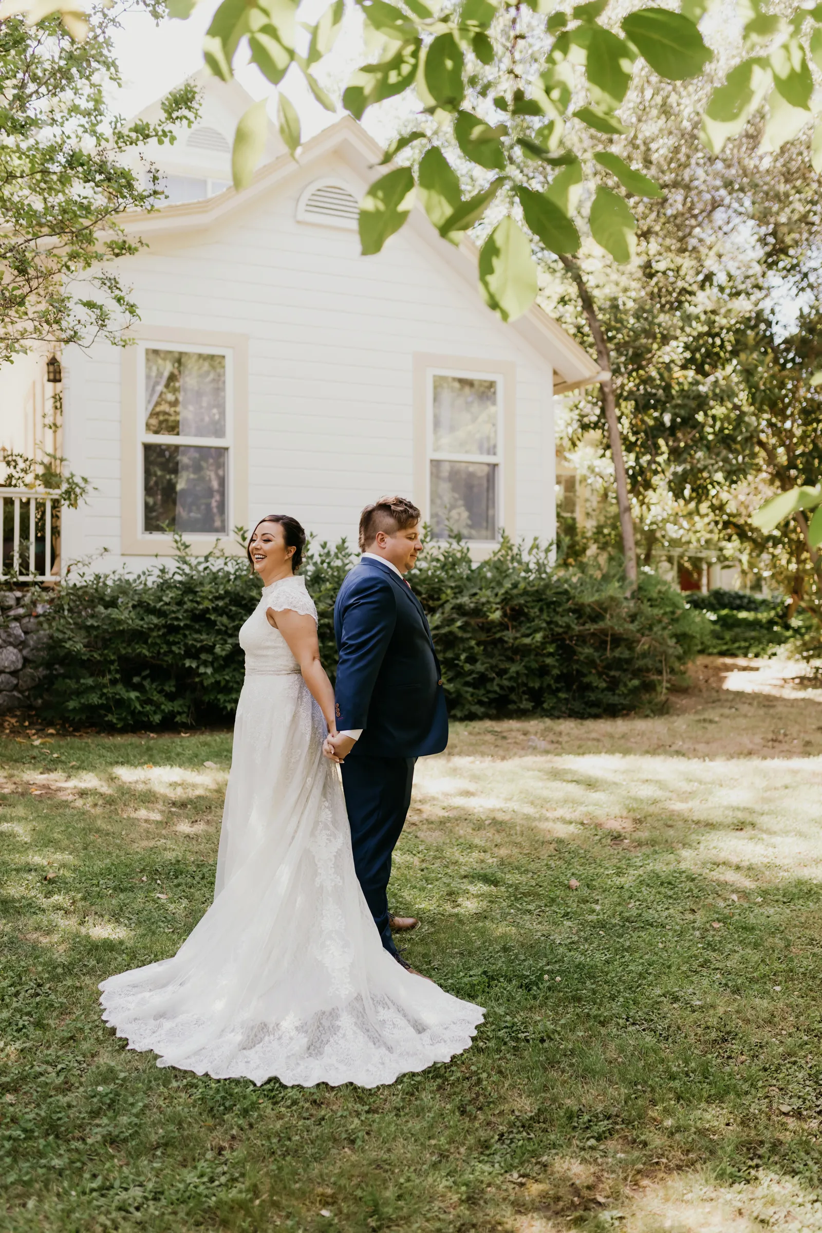 Bride and groom holding hands, while facing away from each other.