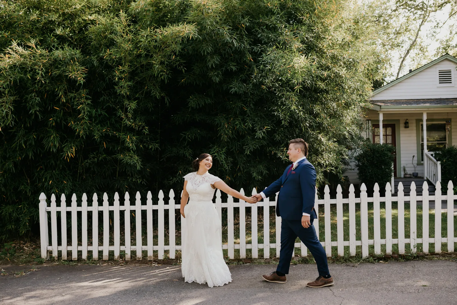 Bride leading her husband down the sidewalk.