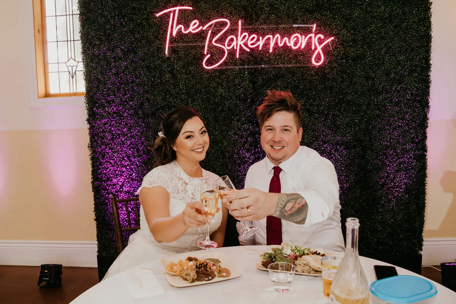 Newlyweds sitting at their sweet heart table and smiling with their rinks.