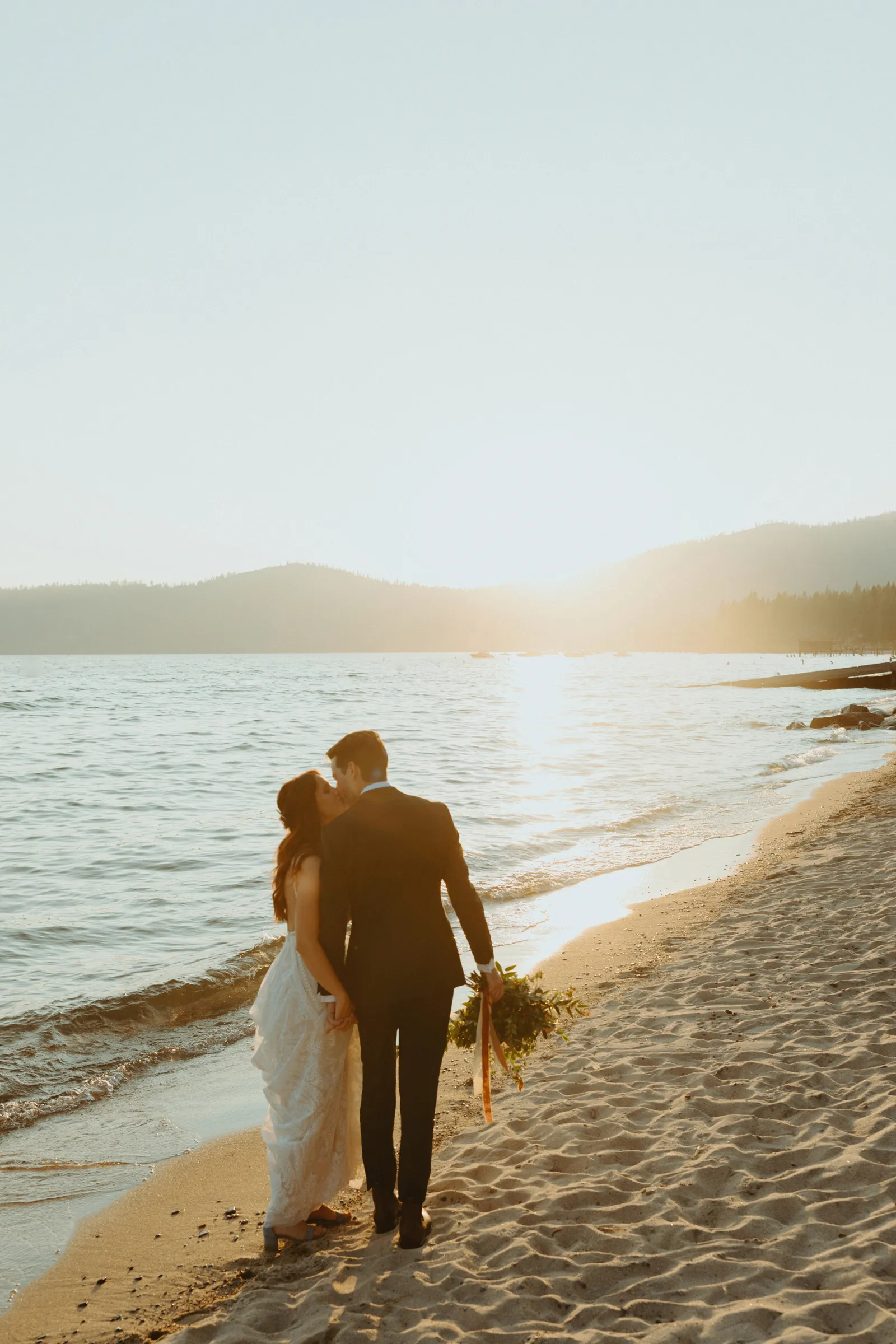 Bride and groom walking into the sunset on the beach.