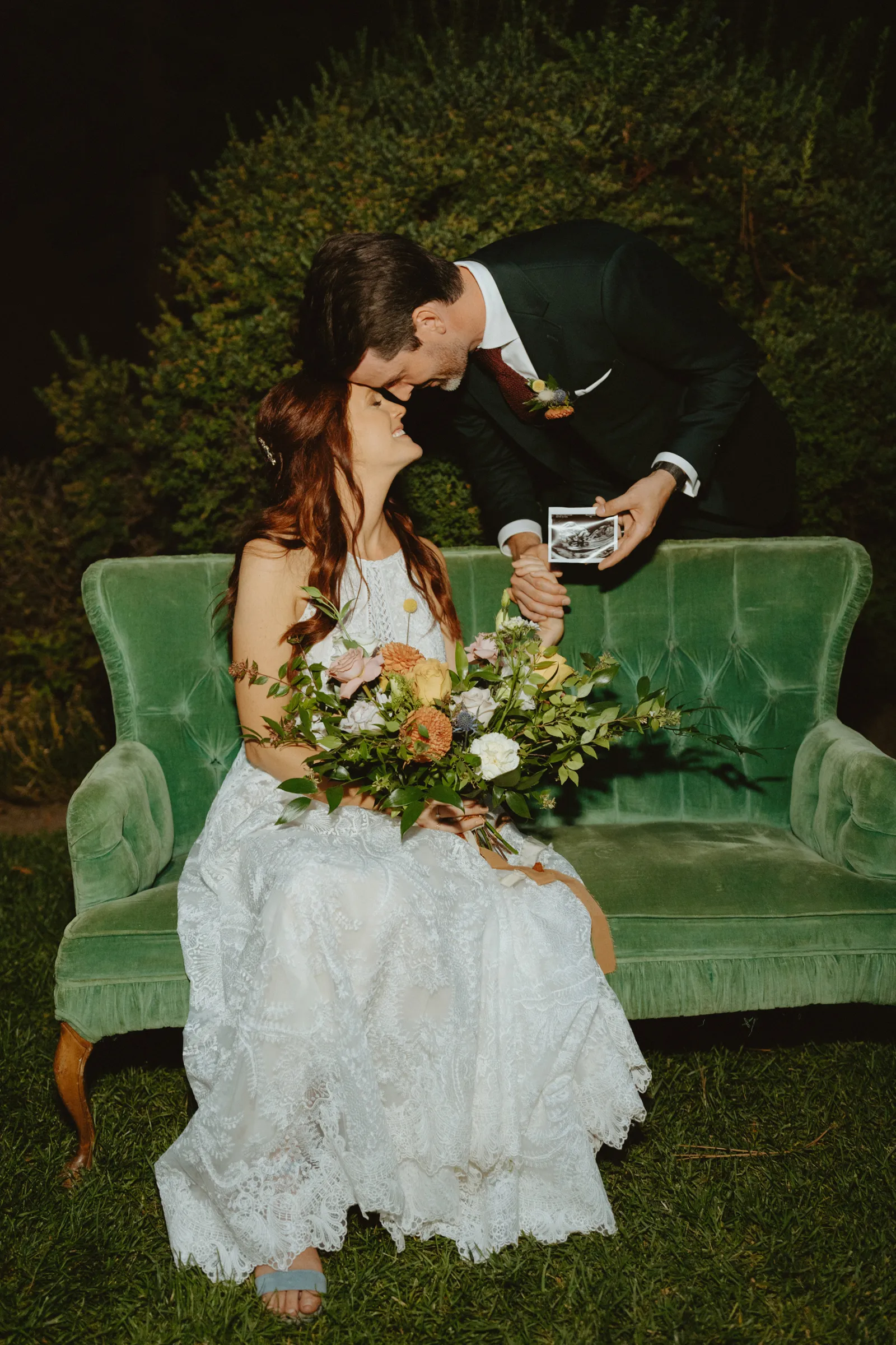 Bride and groom kissing as they reveal their sonogram.