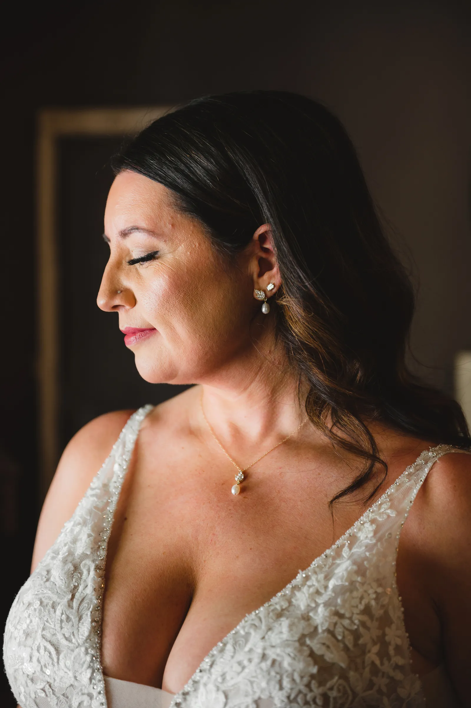 Bride looking to down, to the side, with her eyes closed.