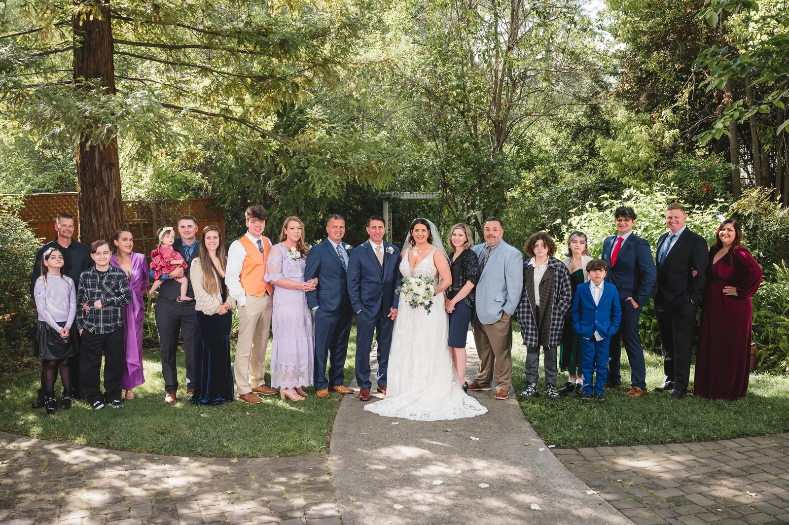 Bride and groom posing with all their guests and smiling at the camera.