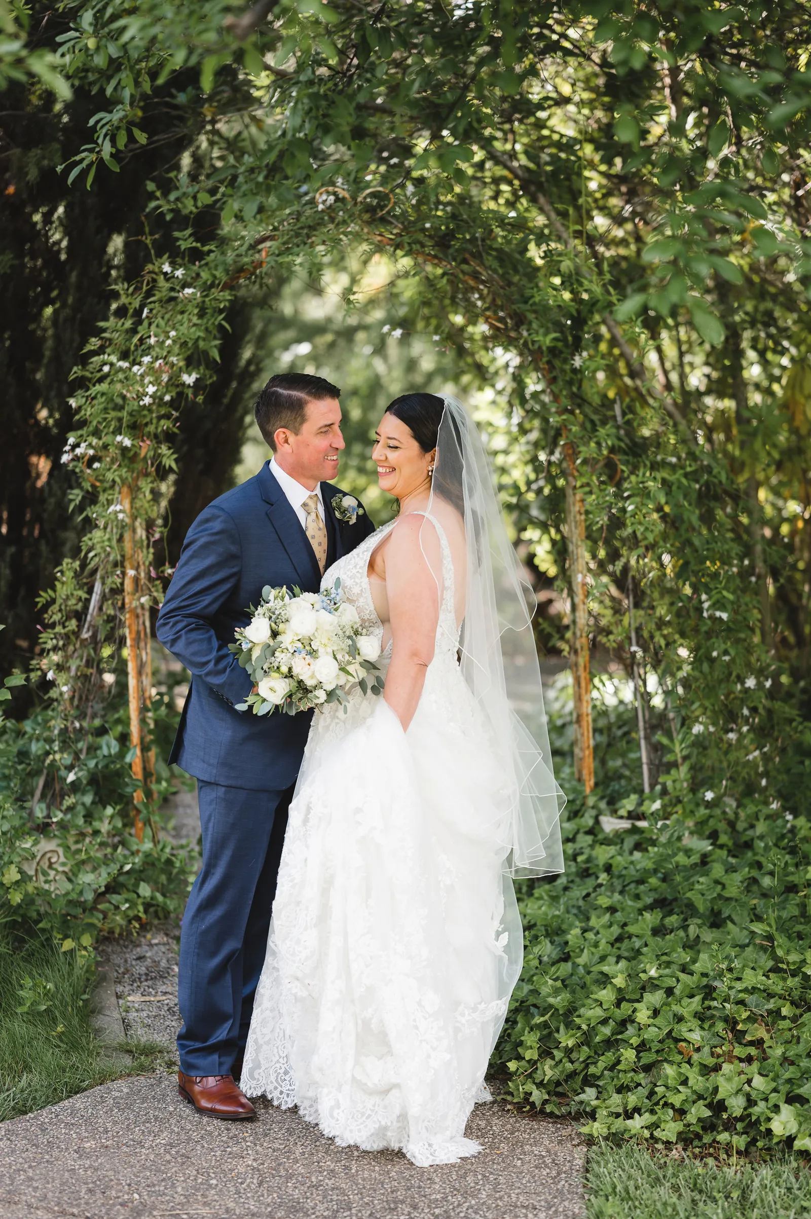 Bride and groom embracing and smiling in the gardens.