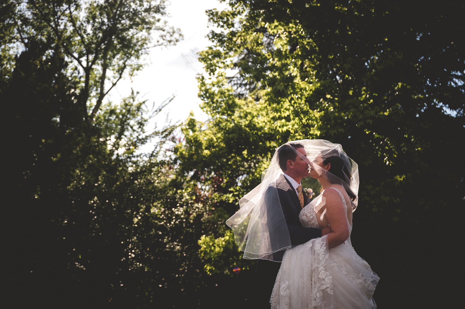 Bride and groom about to kiss inside the bride's veil.