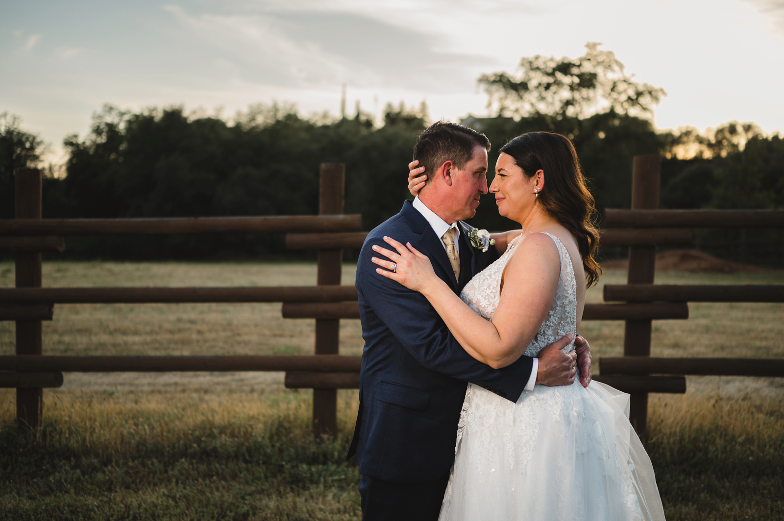 Groom and bride embracing each other outside as the sun sets.