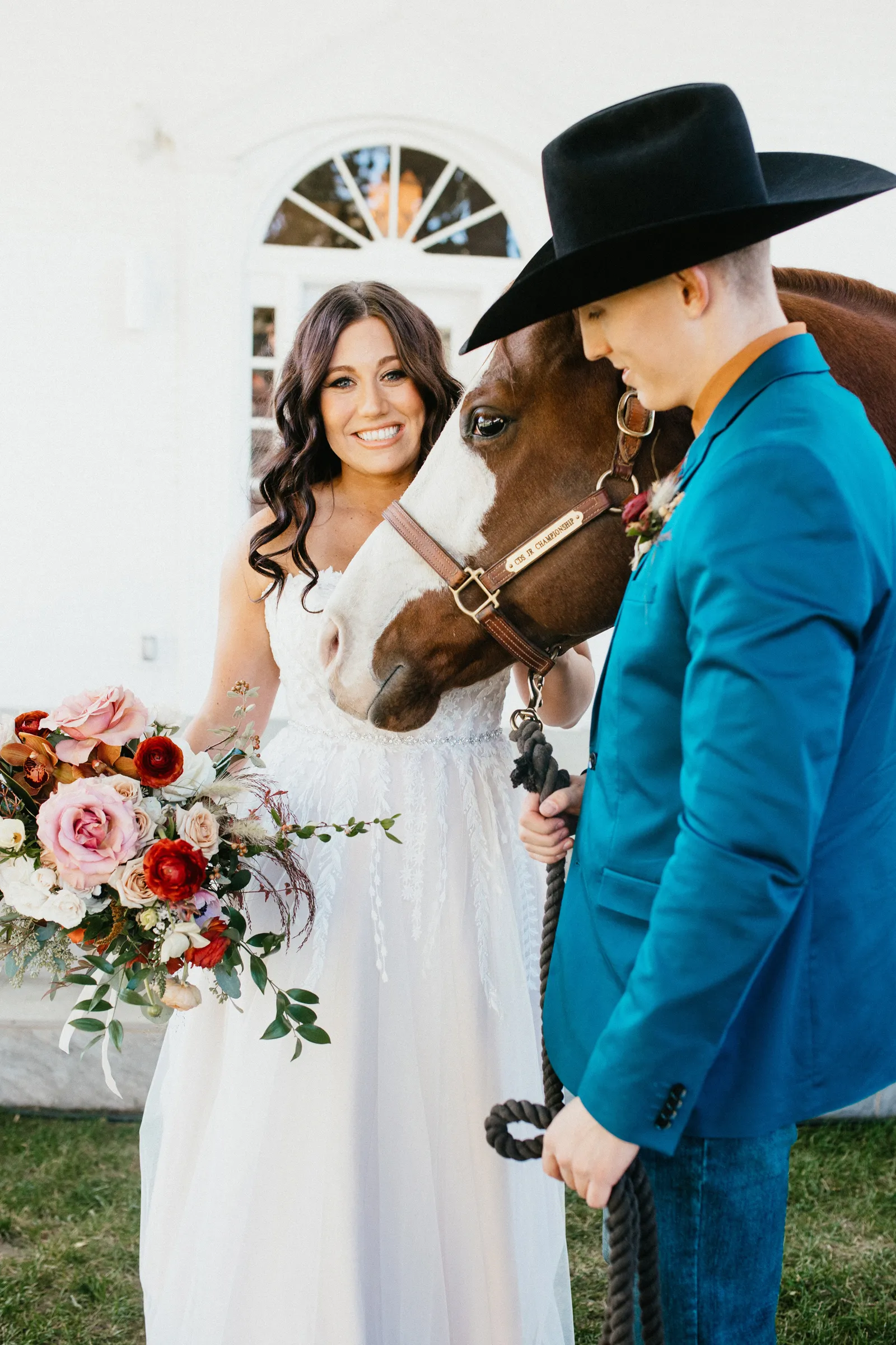 Bride and groom holding the reigns of a horse as they smile.