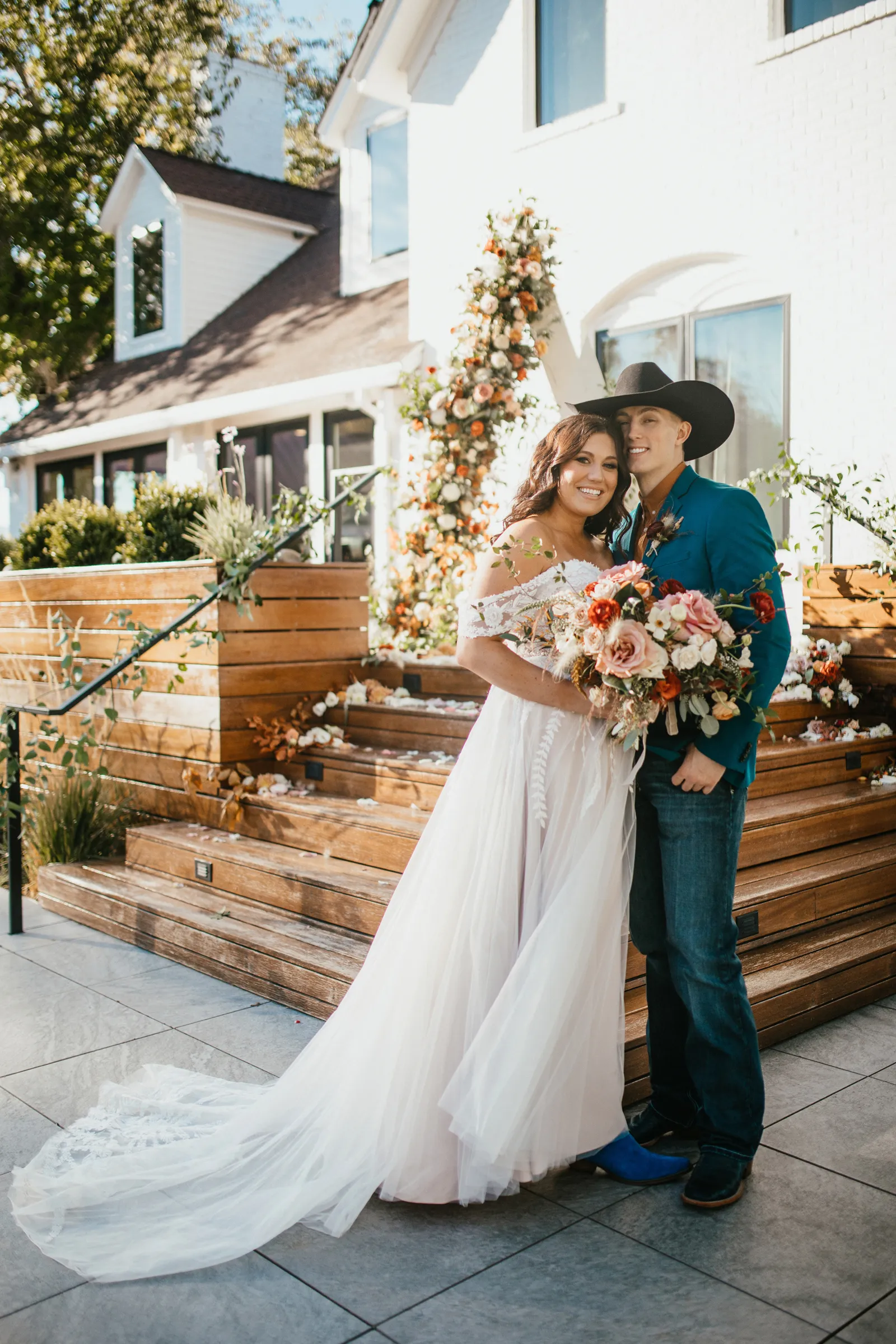 Bride and groom standing next to some stairs with flowers on them.