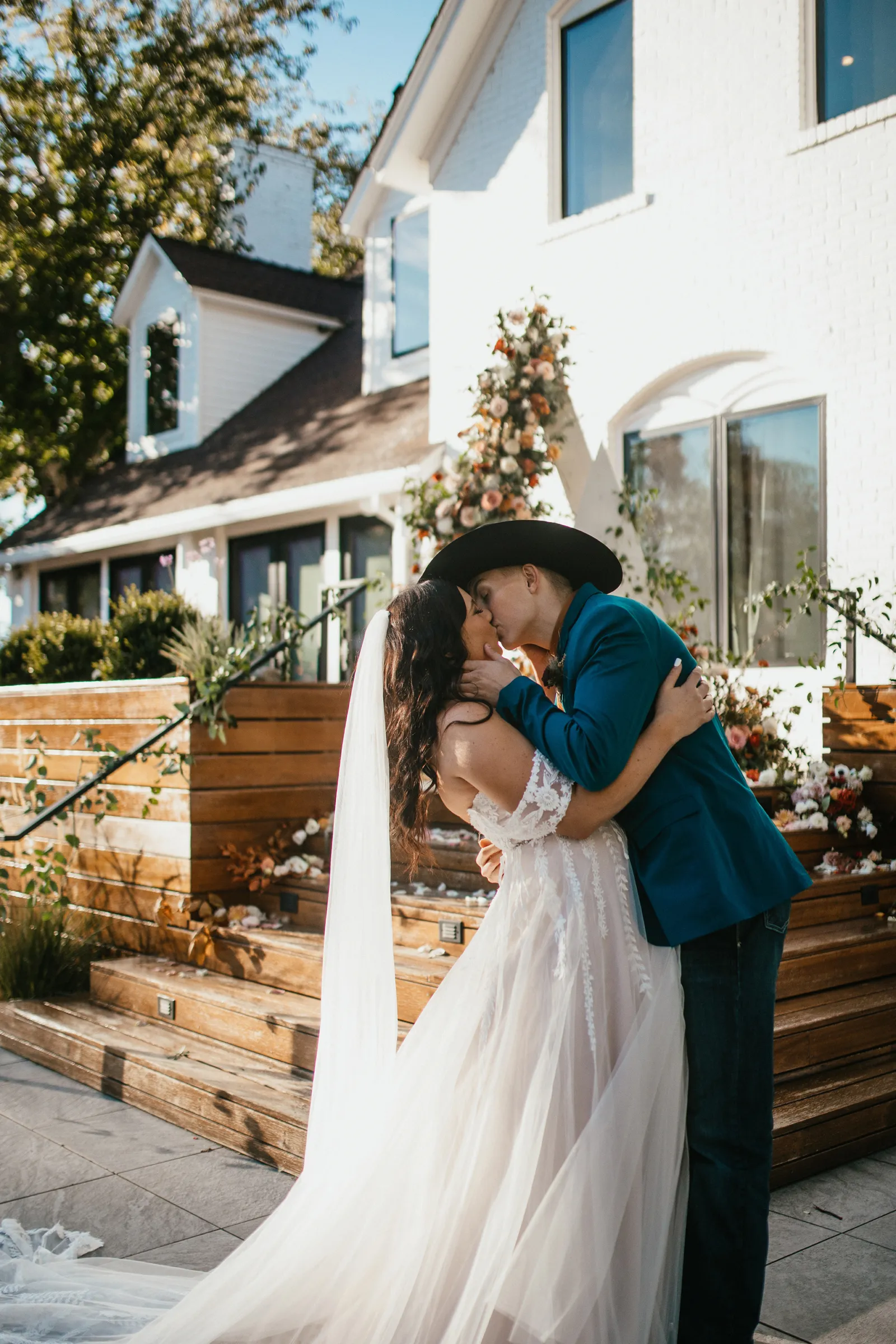 Bride and groom about to kiss in front of stairs covered in florals.