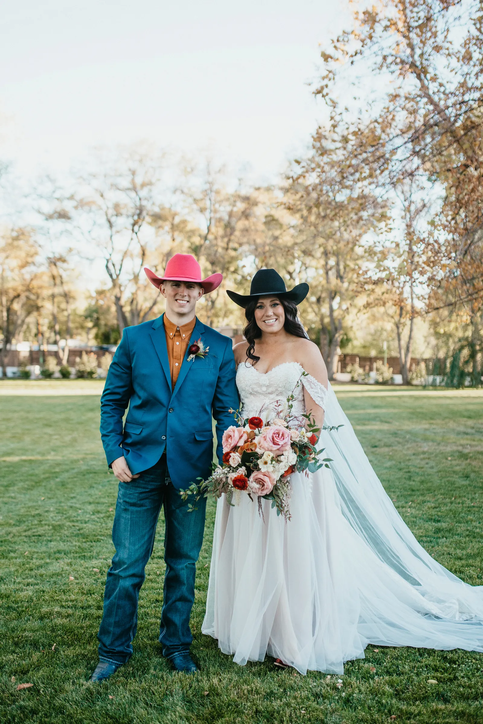 Bride and groom smiling in their cowboy hats.