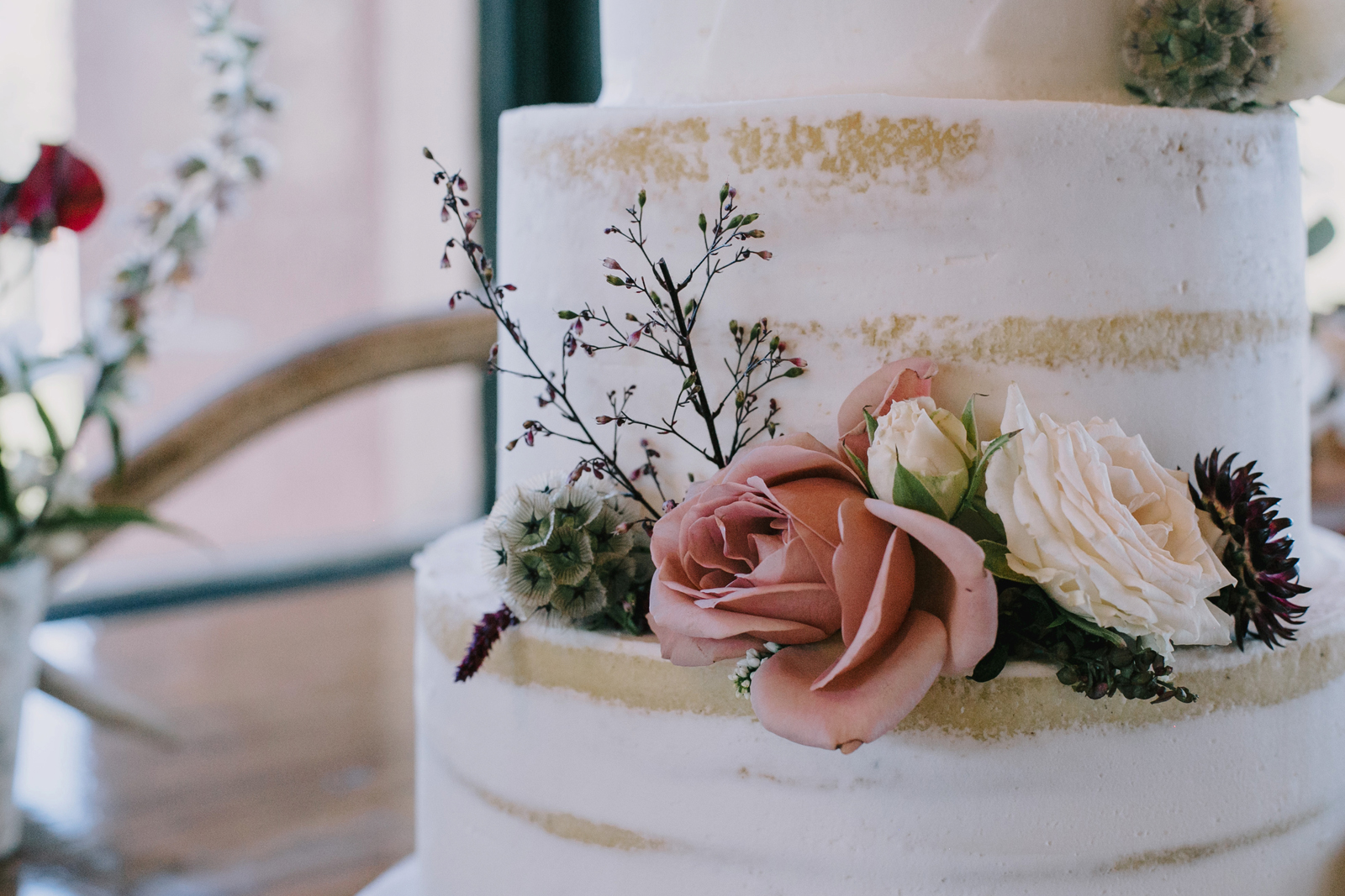 Close up photo of a layered cake with a dusty pink flower.