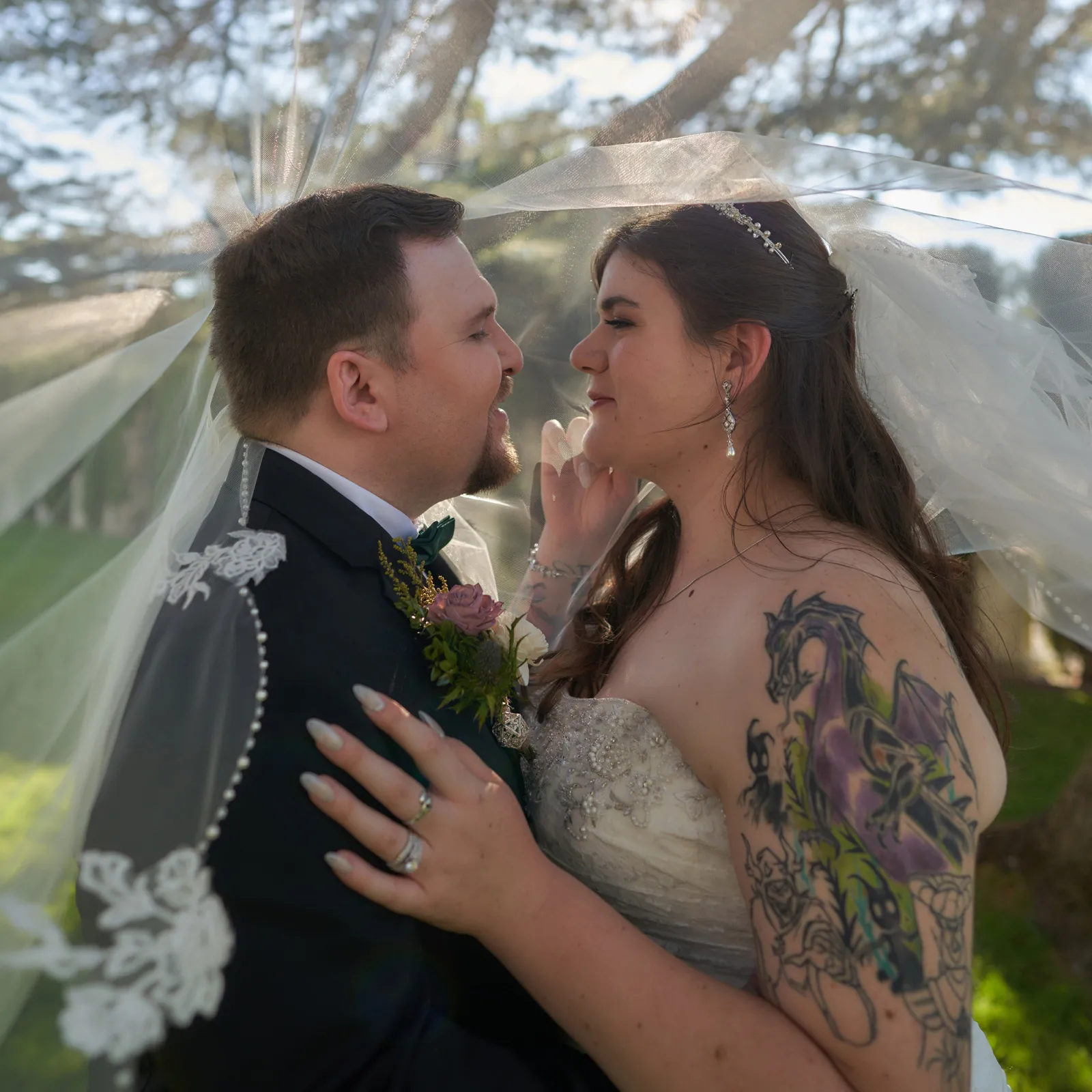 Bride and groom taking wedding photos with JB Wedding Photography, embracing underneath the bride's veil.