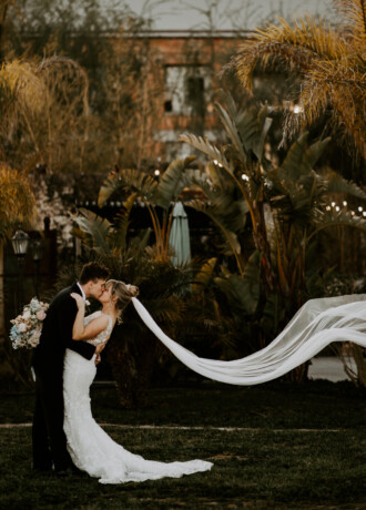 Couple kissing in front of the vintage, modern Old Sugar Mill.