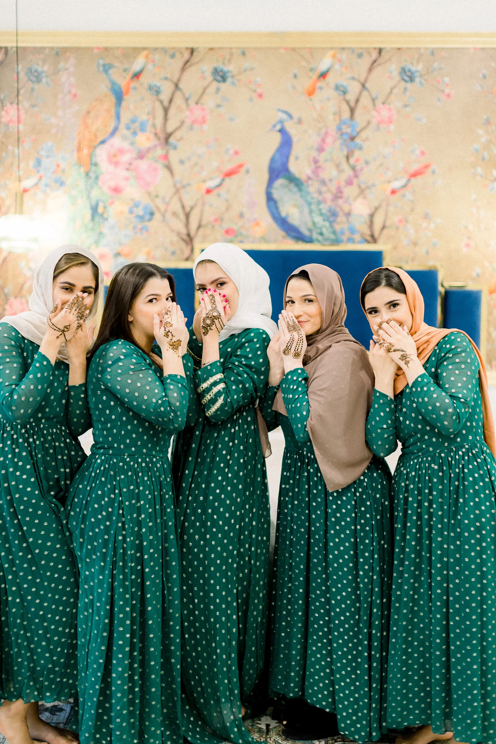 Models in their green gowns posing and showing their hands to the camera.
