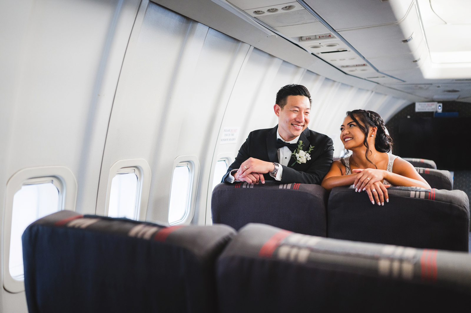 Bride and groom posing together inside an airplane at their elegant aviation museum wedding.