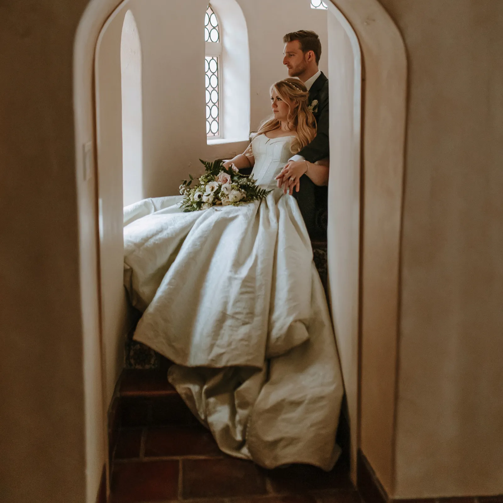 Bride and groom posing together in a stairwell for their featured real wedding.